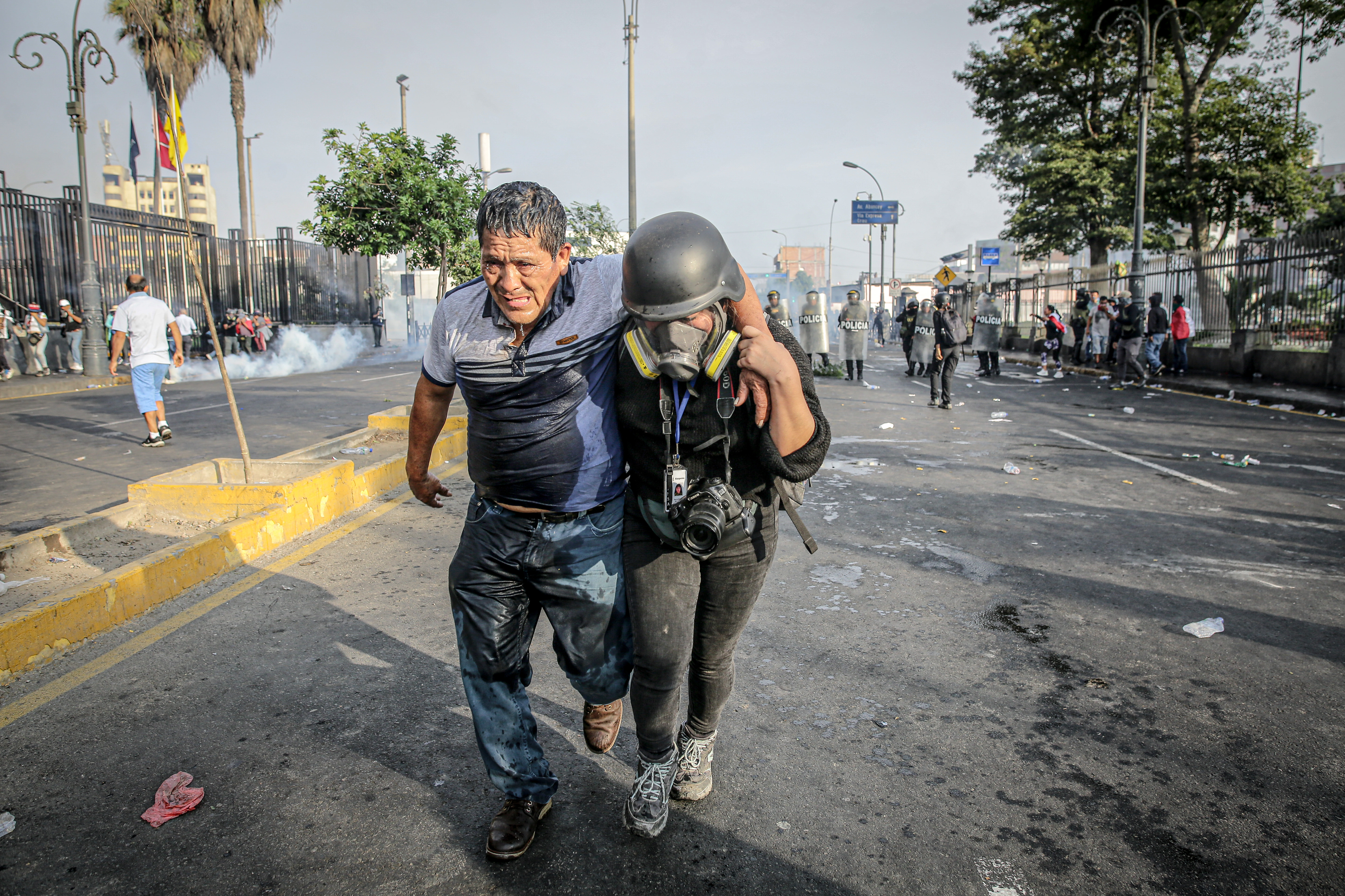 AME7303. LIMA (PERÚ), 19/01/2023.- Una fotorreportera ayuda a un hombre afectado tras los enfrentamientos entre manifestantes y la Policía en el Parque Universitario, durante la llamada "toma de Lima" hoy, en Lima (Perú). Miles de peruanos venidos de diversos puntos del país se congregaron este jueves en la capital en la denominada "toma de Lima", para exigir la renuncia de la presidenta Dina Boluarte, el cierre del Congreso y expresar su hartazgo por el olvido del Estado que consideran que padecen. EFE/ Str