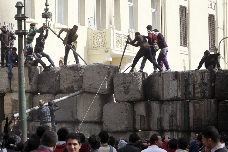 Manifestantes egipcios tratan de derrumbar el muro de cemento que bloquea el paso al Parlamento, en las proximidades de la plaza Tahrir./ EFE