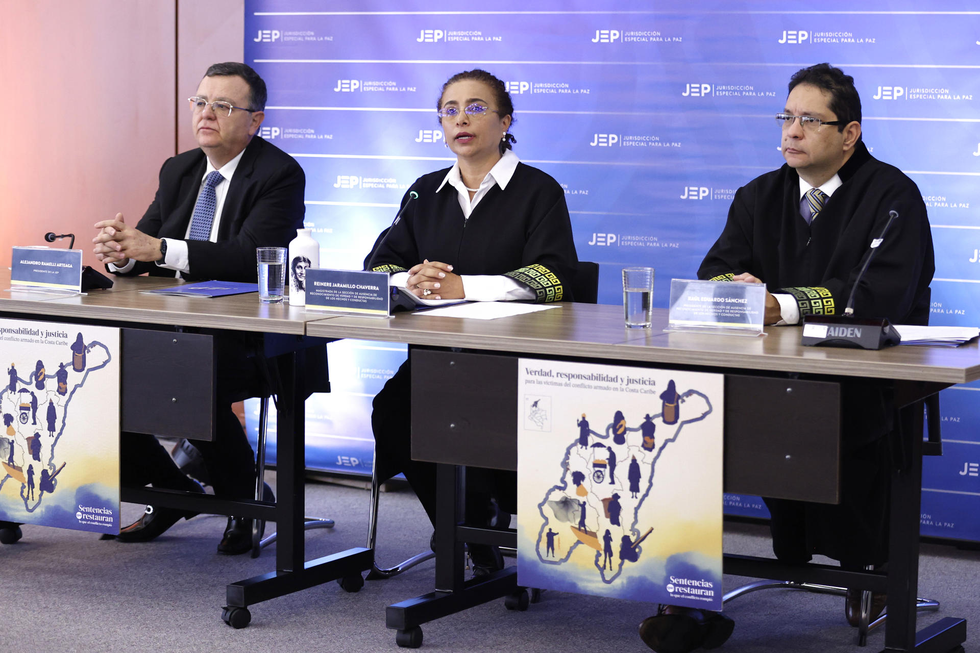 AME9578. BOGOTÁ (COLOMBIA), 19/12/2025.- El presidente de la Jurisdicción Especial para la Paz (JEP), Alejandro Ramelli Arteaga (i); la magistrada de la sección de ausencia de reconocimiento de verdad y responsabilidad (SAVRR), Reinere Jaramillo Chaverra (c), y el presidente de la SAVRR, Raúl Hernando Sánchez, participan en el anuncio de la Primera Sentencia Adversarial Transicional en el proceso del coronel (r) Publio Hernán Mejía Gutiérrez, este viernes en Bogotá (Colombia). La JEP condenó a 20 años de prisión a Hernán Mejía al hallarlo penalmente responsable de crímenes de guerra y de lesa humanidad por 72 asesinatos y desapariciones forzadas de civiles presentados como bajas en combate en el norte del país. EFE/ Mauricio Dueñas Castañeda