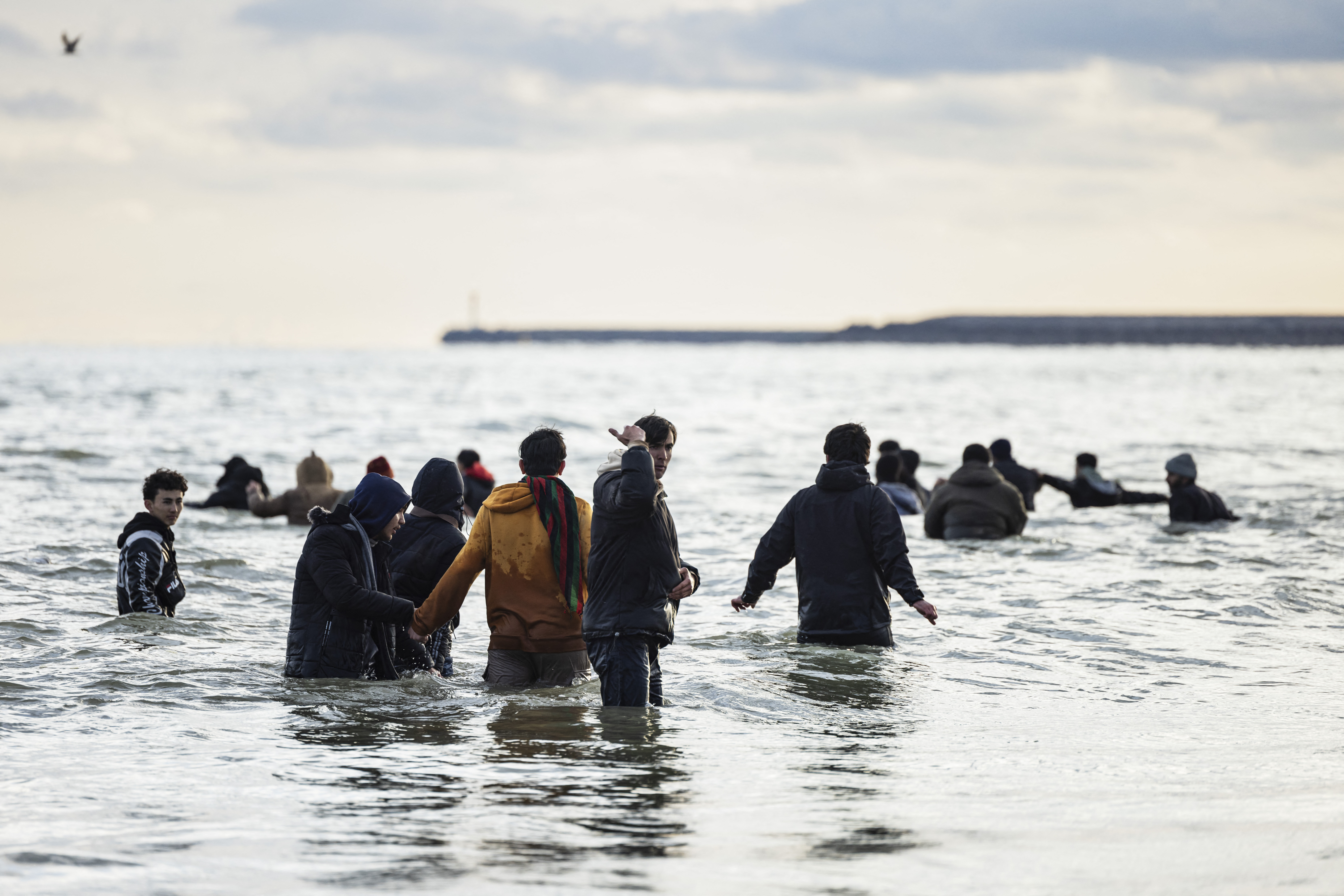 Migrants wade in the water as they attempt to board a smuggler's boat in an attempt to cross the English Channel, on the beach of Gravelines, near Dunkirk, northern France on April 26, 2024.