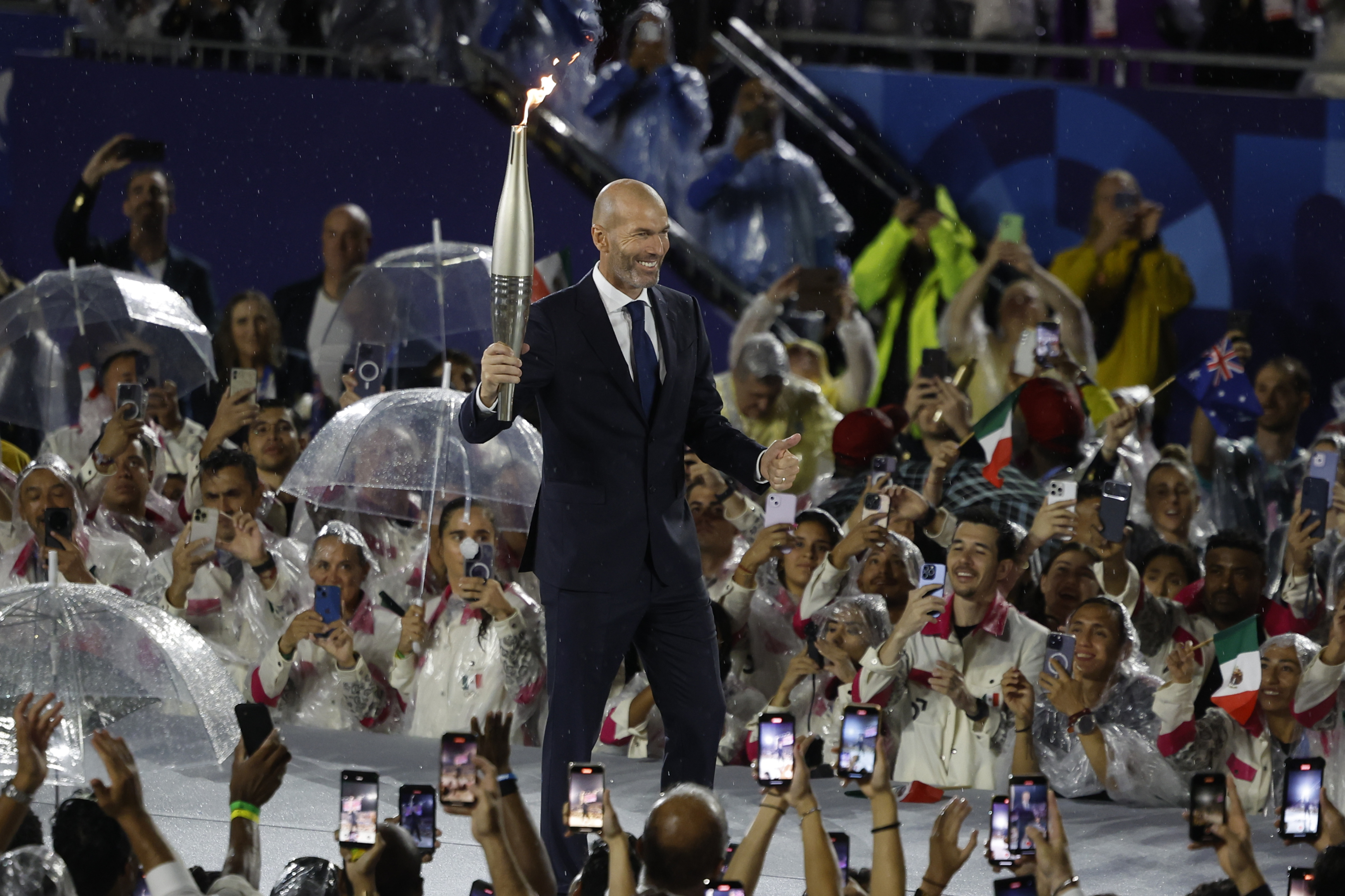 PARÍS (FRANCIA), 26/07/2024.- El exfutbolista Zinedine Zidane porta la antorcha olímpica en la Plaza del Trocadero durante la ceremonia de inauguración de los Juegos Olímpicos de París 2024, este viernes en la capital francesa. EFE/Juanjo Martín