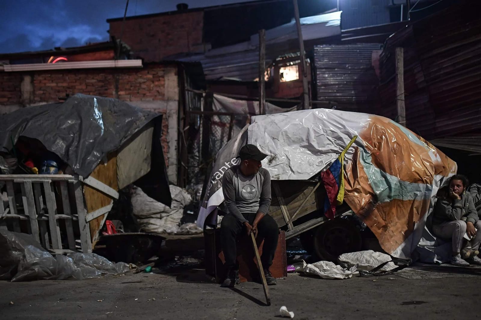 Un hombre sentado junto a un carro del reciclaje