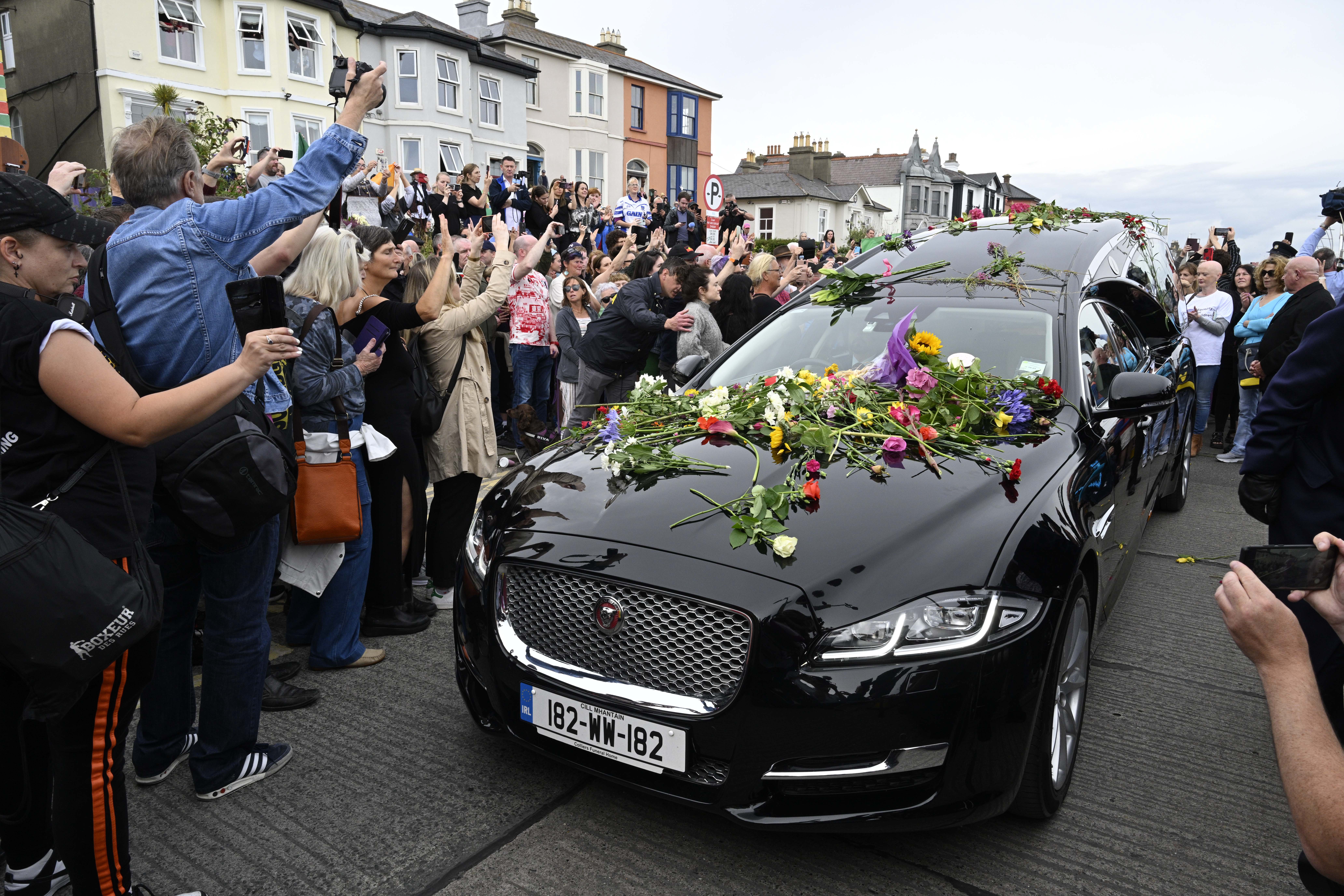 Bray (Ireland), 08/08/2023.- Fans gather for a 'last goodbye' to the Irish singer Sinead O'Connor as her hearse passes by her former home in Bray, Co Wicklow, Ireland, 08 August 2023. The funeral cortege passed by her old home on the way to the private burial service for the 56-years old singer, who was found dead at her home in London on 26 July 2023. (Irlanda, Londres) EFE/EPA/Bryan Meade
