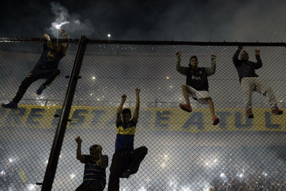 Aficionado de Boca Juniors trepan la malla en La Bombonera. Foto: AFP