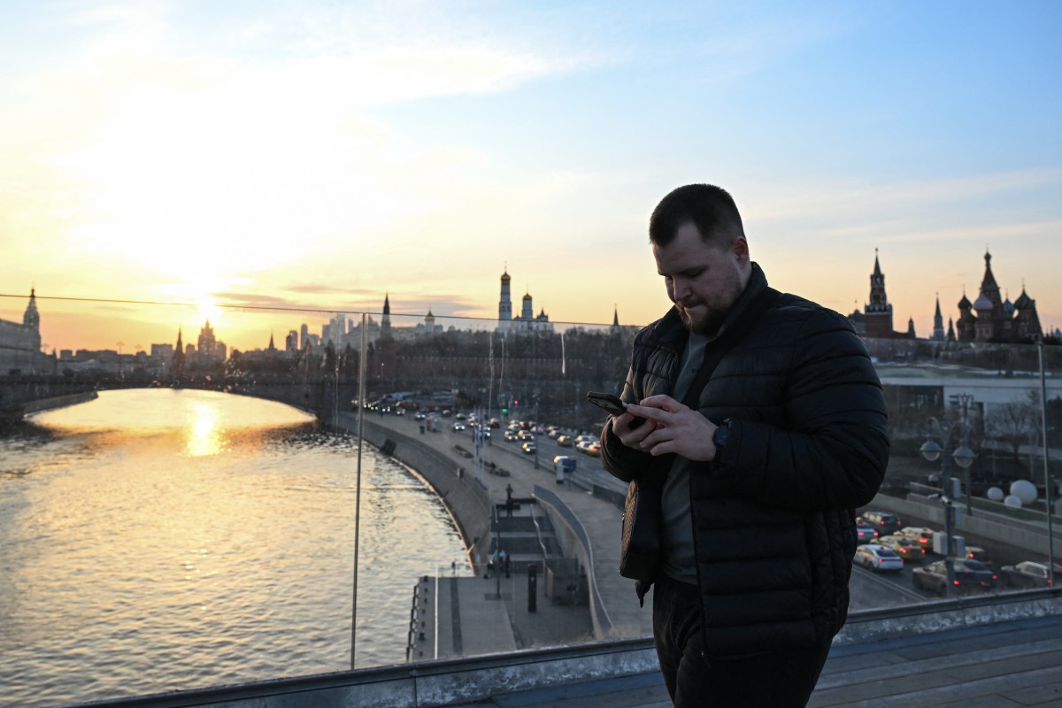 A man uses his smartphone on the Floating bridge (Paryashiy bridge) in the Zaryadye park in central Moscow on March 17, 2026.