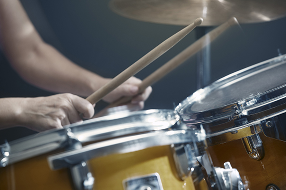Close up of hands with drumsticks and drum set --- Image by © Arman Zhenikeyev/Corbis