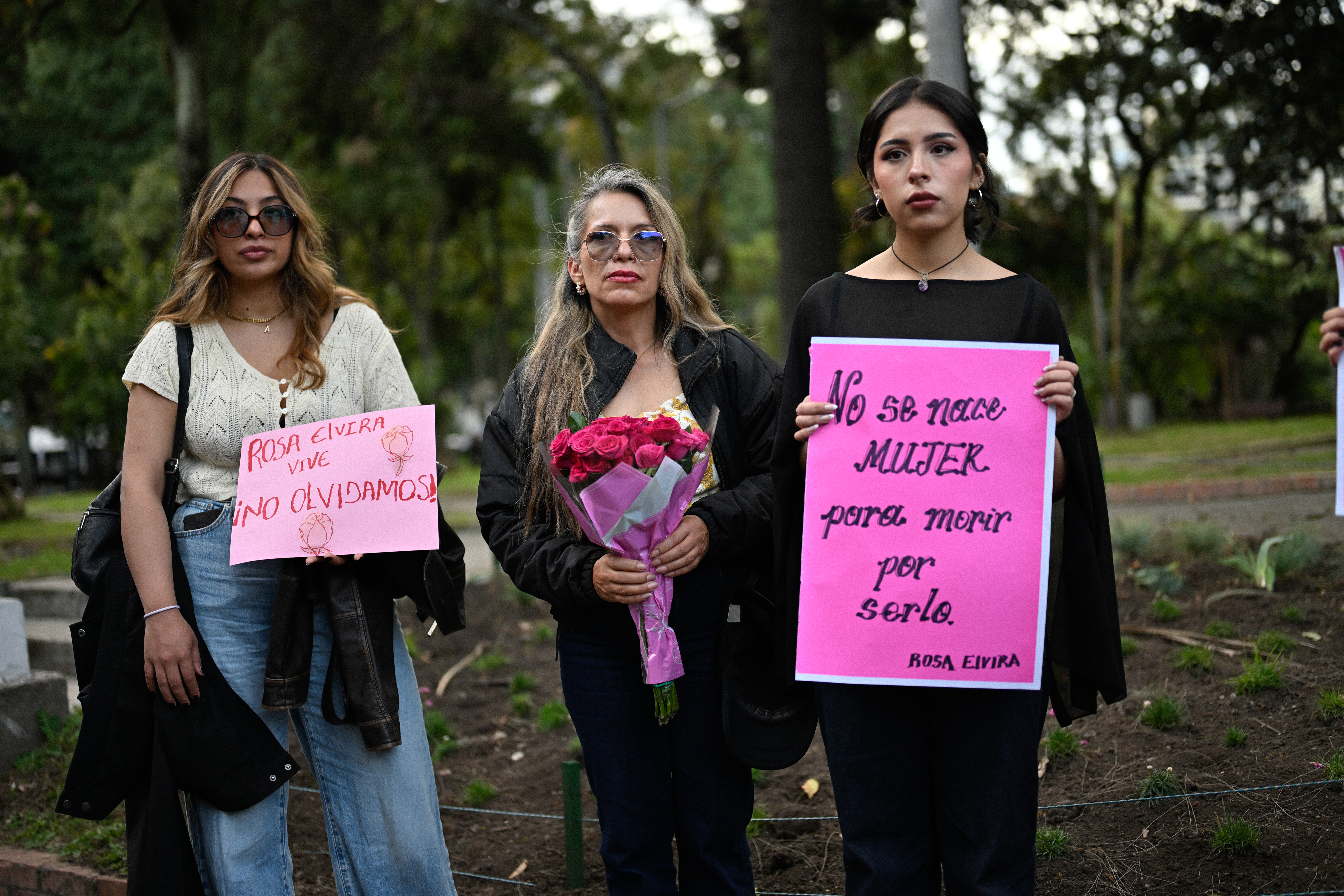 Tres mujeres acompañan el acto con flores y carteles. El feminicidio de Rosa Elvira Cely marcó un punto de inflexión en la discusión sobre la violencia de género en Colombia. A partir de su caso, su familia impulsó una campaña que contribuyó a la creación de la Ley Rosa Elvira Cely, mediante la cual el feminicidio fue reconocido como un delito autónomo en el país.