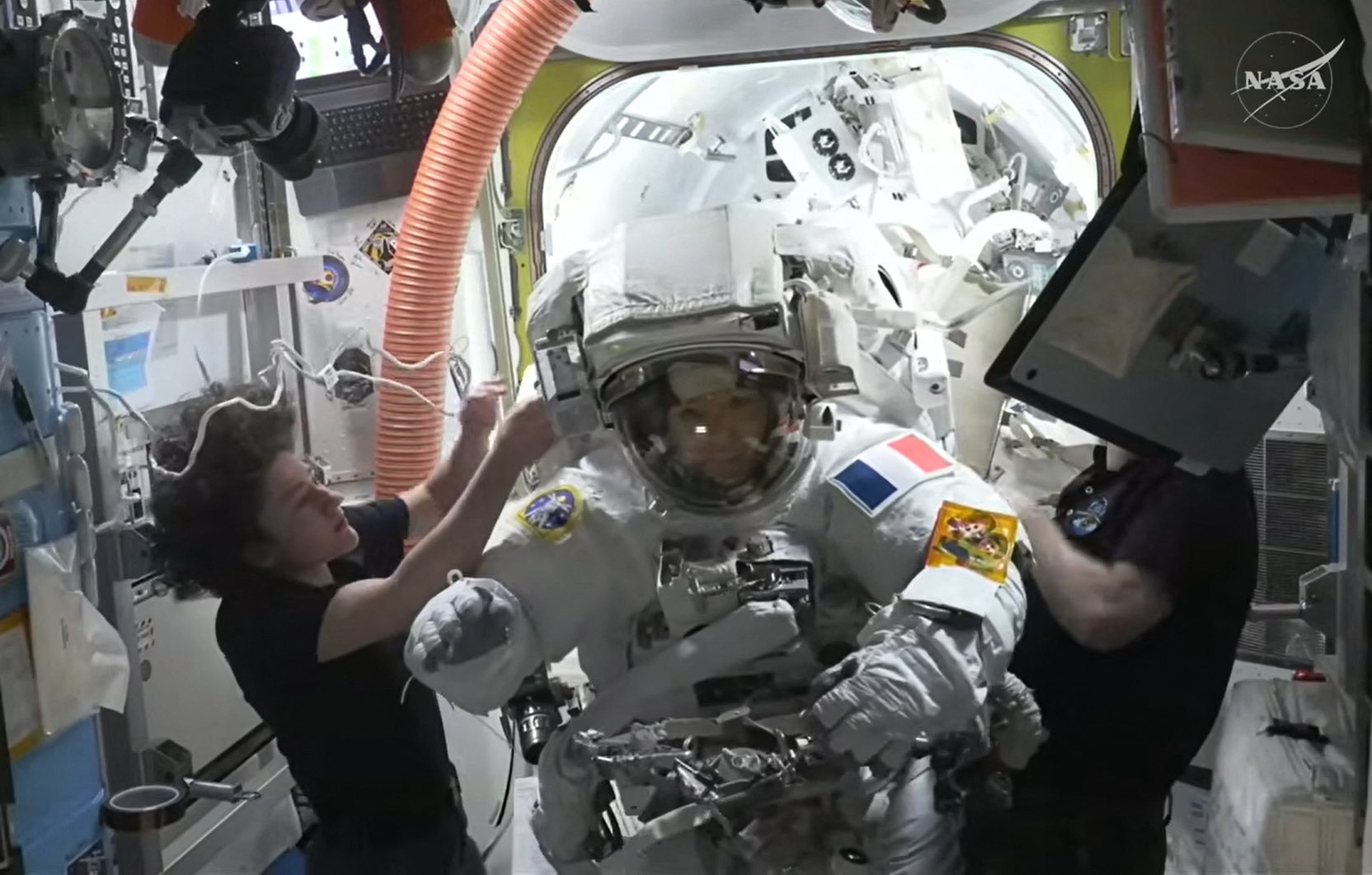 This August 18, 2026, frame grab from a NASA live video stream shows European Space Agency (ESA) French astronaut Sophie Adenot (C) returning back inside the International Space Station (ISS) after her spacewalk where she and NASA astronaut Anil Menon replaced a space-to-ground antenna on the orbital complex, according to NASA.