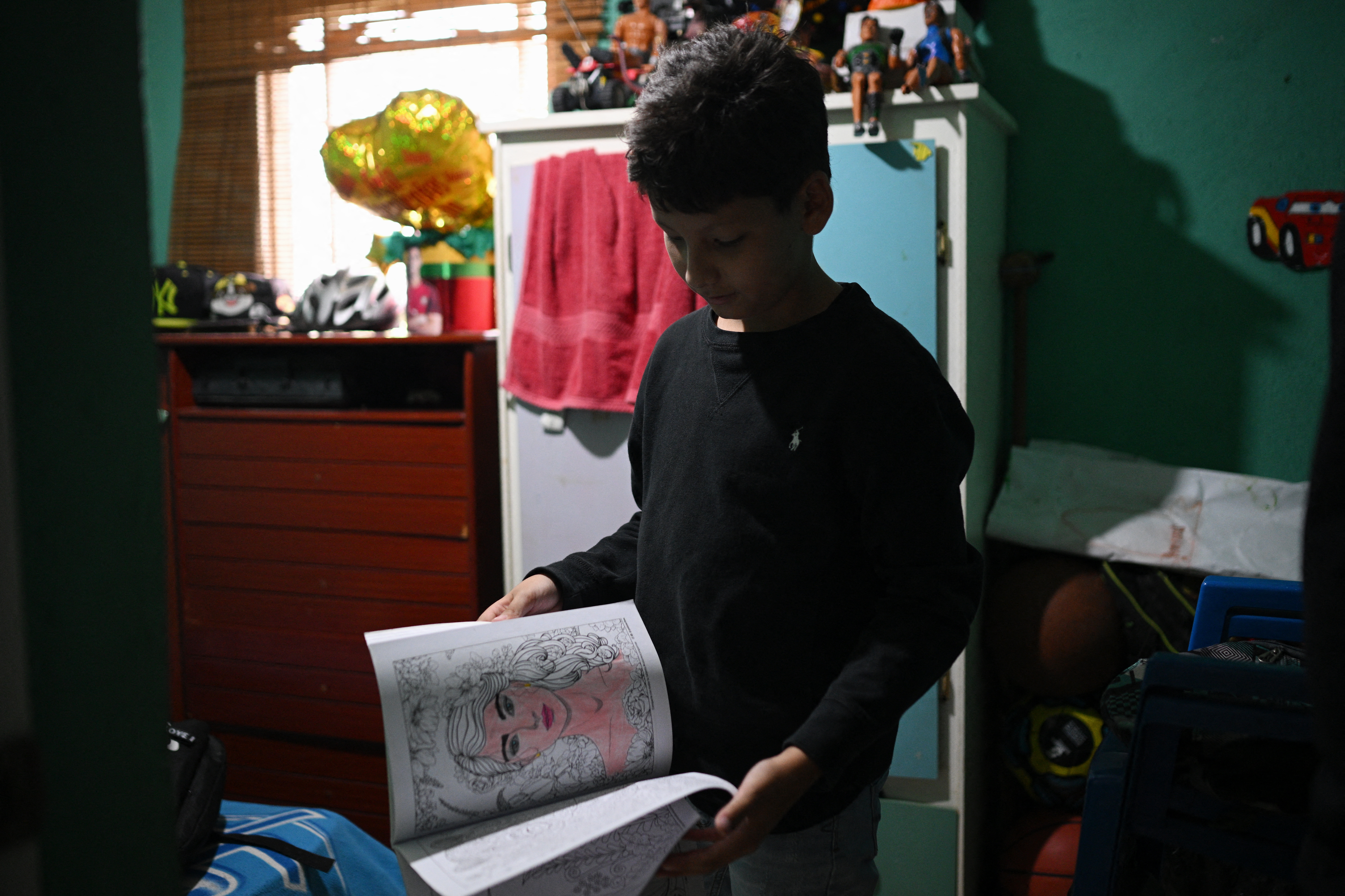 Venezuelan student Randy Ordonez shows his notebooks during an interview with AFP after presenting the math and language tests of the National Recreational Olympics in Montalban town, Carabobo State, Venezuela, on June 15, 2024.