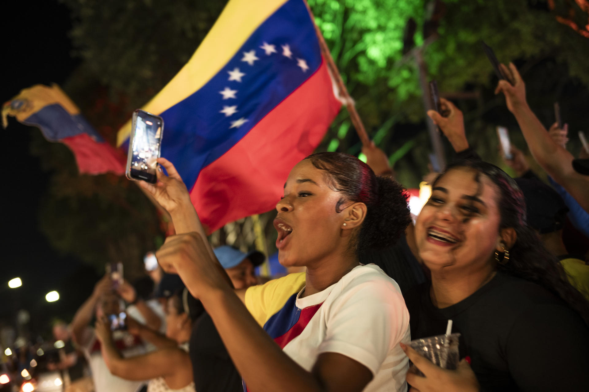 AME2056. MANAOS (BRASIL), 03/01/2026.- Personas sostienen banderas de Venezuela durante una manifestación este sábado, en Manaos (Brasil). La captura de Nicolás Maduro, y de su esposa, Cilia Flores, en la madrugada de este sábado por parte de EE.UU., en una operación denominada Resolución Absoluta, que incluyó varios bombardeos sobre el país, ha dividido al continente americano entre quienes celebran el fin del mandato del chavista y quienes denuncian las acciones estadounidenses como ilegales. EFE/ Raphael Alves