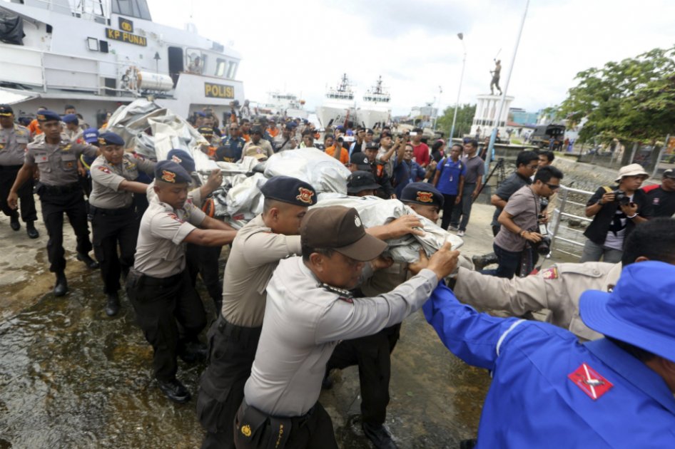 Policías indonesios transportan parte del fuselaje recuperado del avión de AirAsia siniestrado.