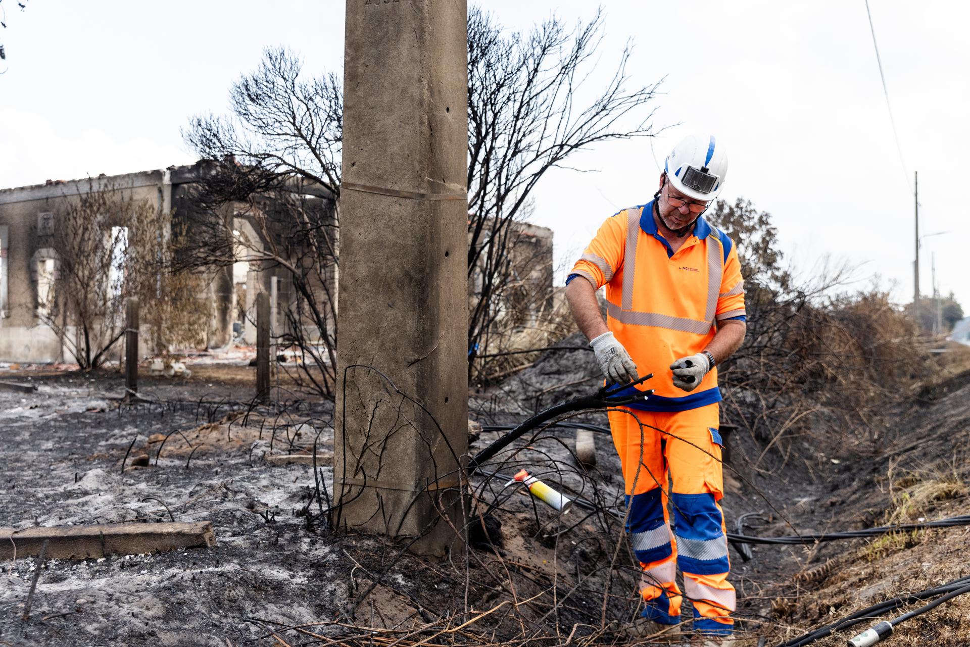 Le Porge (France), 30/07/2026.- NGE Energie Solutions personnel work to secure power lines in front of fire damaged houses following wildfires in Le Porge, France, 30 July 2026. Most of the residents of the town evacuated as the fires approached Le Porge. (Francia) EFE/EPA/Sophie Garcia