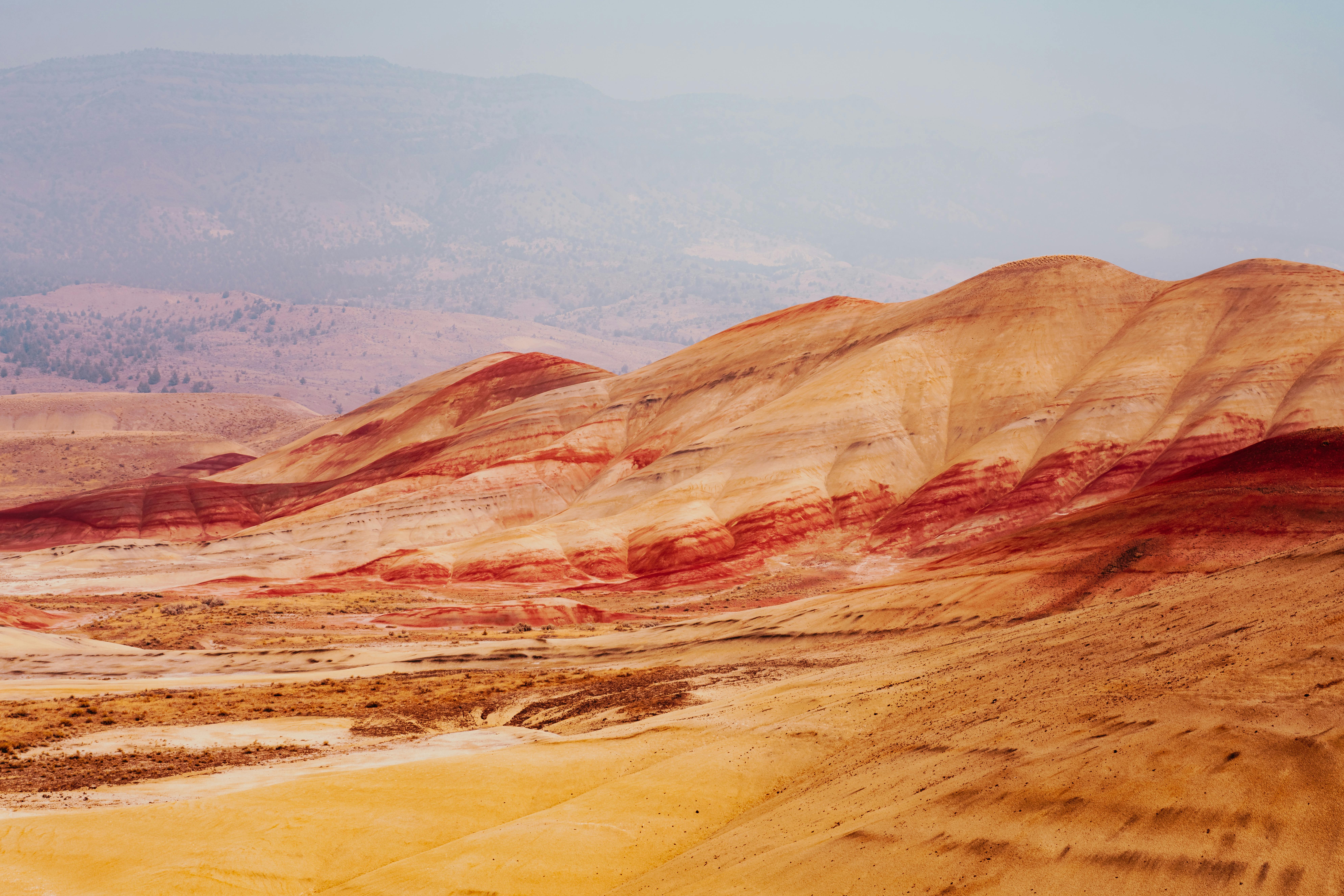 Painted Hills es una de las formaciones más sorprendentes de Estados Unidos y forma parte del Monumento Nacional John Day Fossil Beds, en el estado de Oregón. Sus colinas exhiben capas de tonos amarillos, dorados, rojizos y negros creadas por millones de años de erosión, cenizas volcánicas y sedimentos minerales, dando la impresión de un paisaje de otro planeta. El lugar puede recorrerse a través de senderos sencillos y miradores panorámicos que permiten admirar de cerca sus colores sin alterar este delicado entorno geológico.