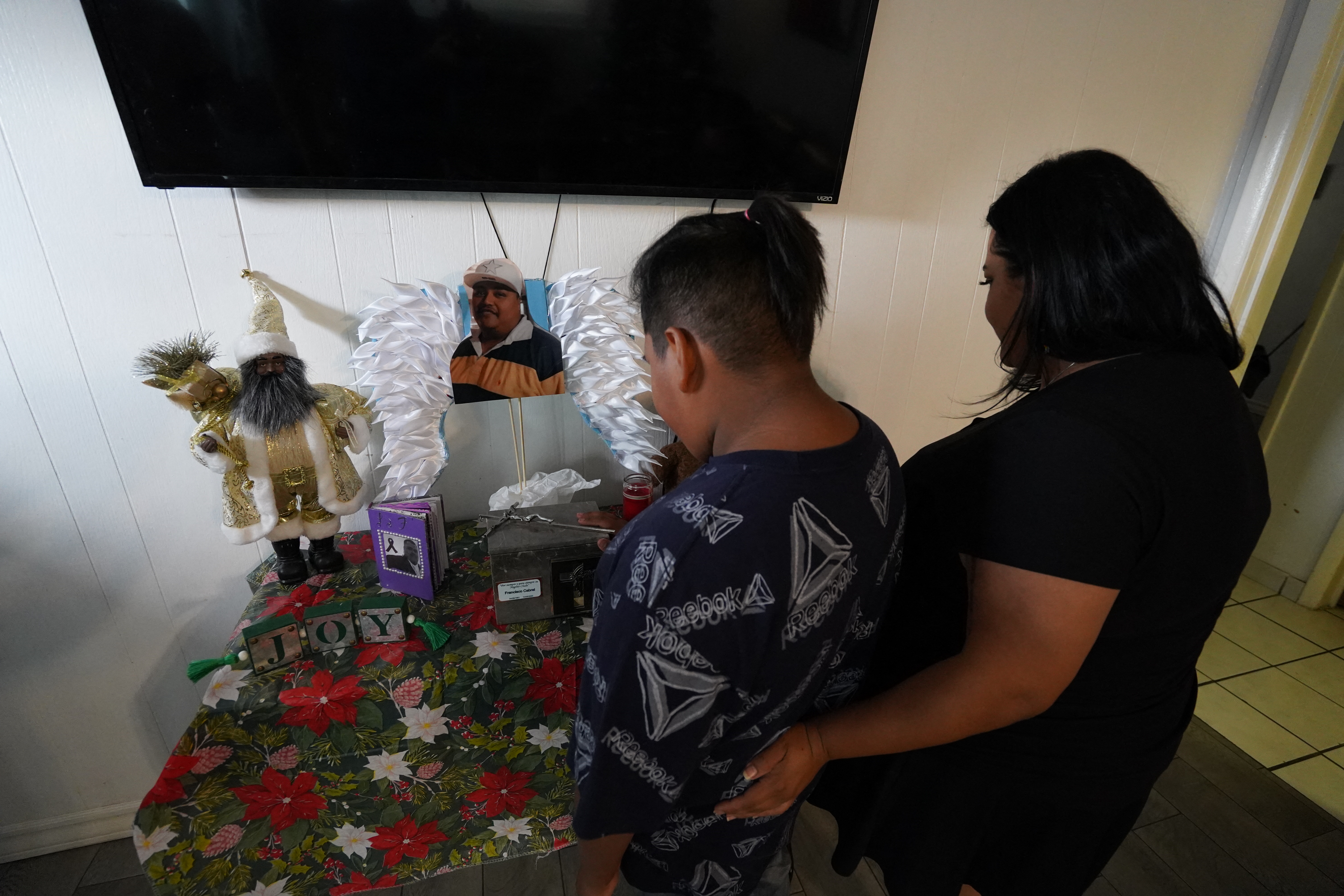Mirna Cabral (37) and her son Damian Cabral (10) stand by a shrine with photos and the ashes of their late husband and father Francisco Cabral at their home on November 25, 2024, in El Paso, Texas.