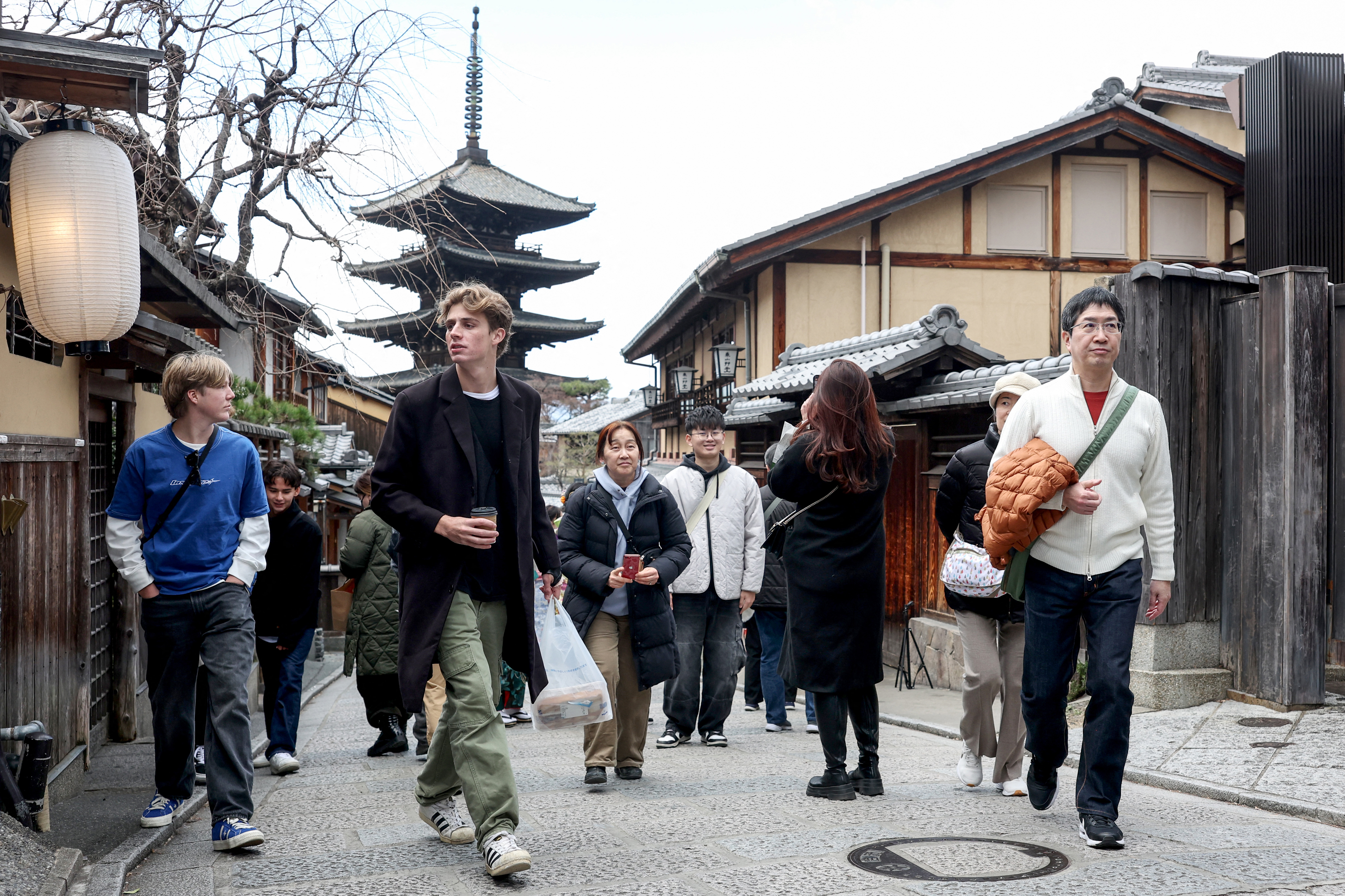 Tourists walk through the streets by Yasaka Pagoda (behind) during a visit to the city of Kyoto on January 13, 2025.