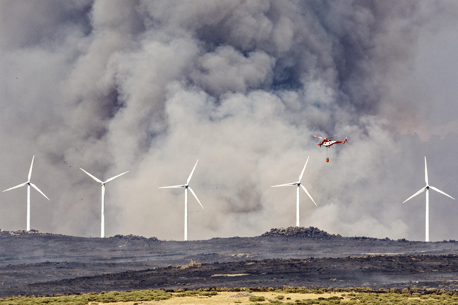 ÁVILA (CASTILLA Y LEÓN), 15/08/2025.- Un helicóptero trabaja este viernes, en labores de extinción del incendio en las proximidades de Urraca-Miguel, barrio anexionado de Ávila capital, y cuyos vecinos han sido evacuados pasadas las 16 horas por la proximidad de las llamas. EFE/ Raúl Sanchidrián