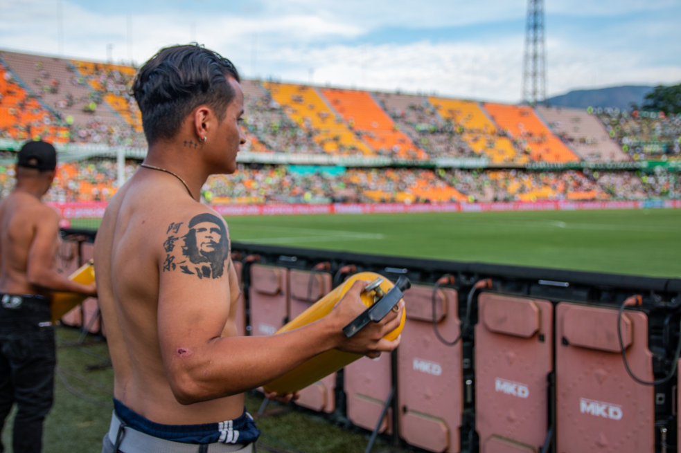 La visita de los excombatientes al Atanasio se enmarca dentro de la iniciativa: "A la cancha por primera vez", que Pueblo Verdolaga lleva a cabo desde 2015 para llevar al estadio a personas de las poblaciones más vulnerables. “Hemos traído a niños, niñas y adolescentes de barrios que están por fuera del Plan de Ordenamiento Territorial. Hemos traído a abuelos de comedores comunitarios, y a un montón de pelados de escuelas de futbol. El semestre anterior trajimos habitantes de calle y eso a nosotros nos generó la necesidad de buscar a poblaciones vulnerables de diferentes lugares no solamente de Medellín, sino del departamento e incluso del país que sean susceptibles de ser traídas”, explica Juan Esteban Mosquera, líder de Pueblo Verdolaga. Para la visita de los excombatientes el pasado domingo, Pueblo Verdolaga tuvo el apoyo de la Misión de Verificación de la ONU, el PNUD, el Museo Casa de la Memoria, la Agencia para la Reincorporación y Normalización (ARN), entre otras organizaciones.