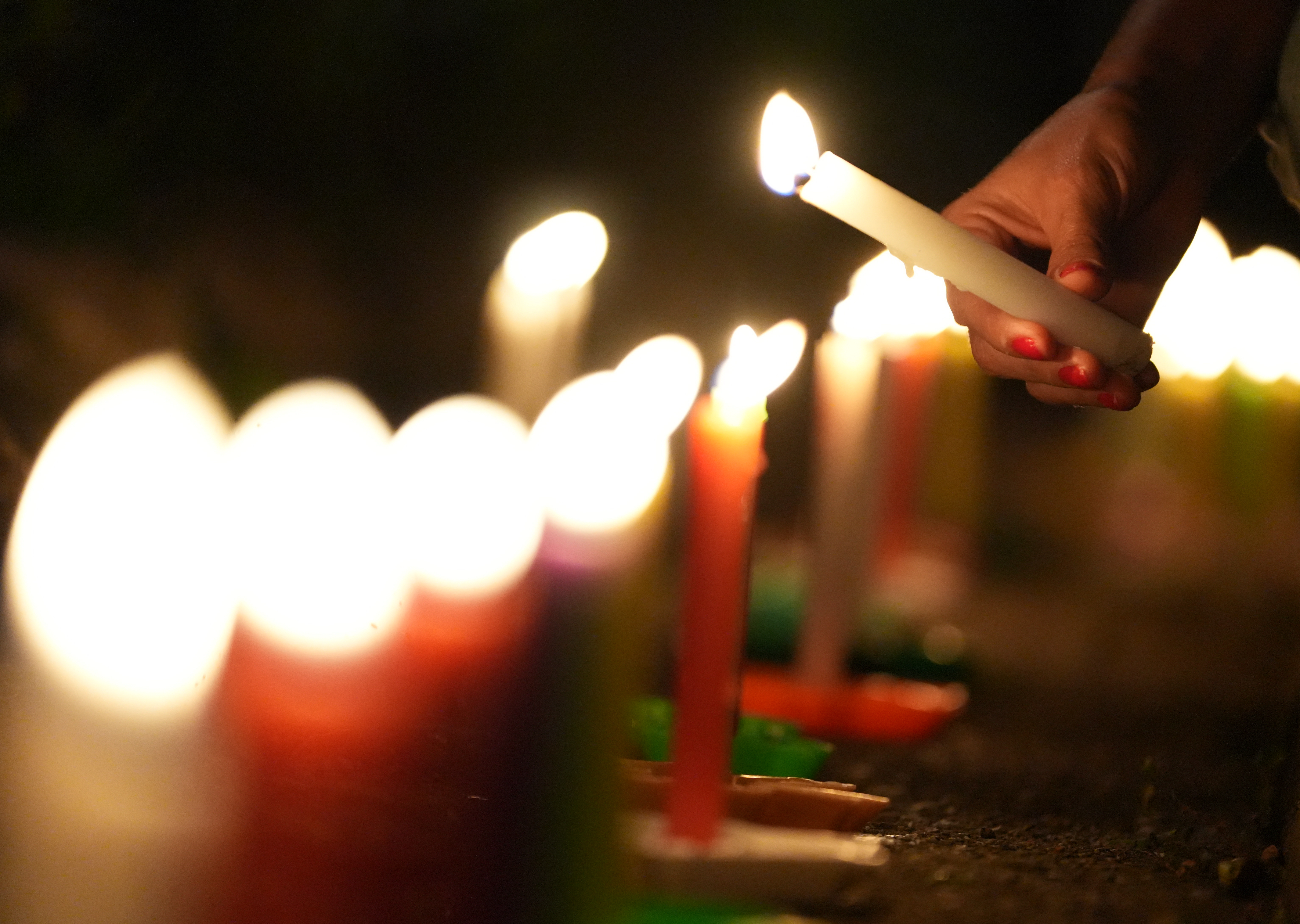 AME4025. CALI (COLOMBIA), 07/12/2024.- Una persona enciende velas durante la tradicional Noche de las Velitas este sábado en Cali (Colombia). La tradicional Noche de las Velitas, que marca el inicio de la Navidad en Colombia, se vivió este sábado en el que familias a lo largo y ancho del país se reunieron en viviendas, edificios, plazas y parques para compartir comida y golosinas y disfrutar de los alumbrados navideños. EFE/Ernesto Guzmán