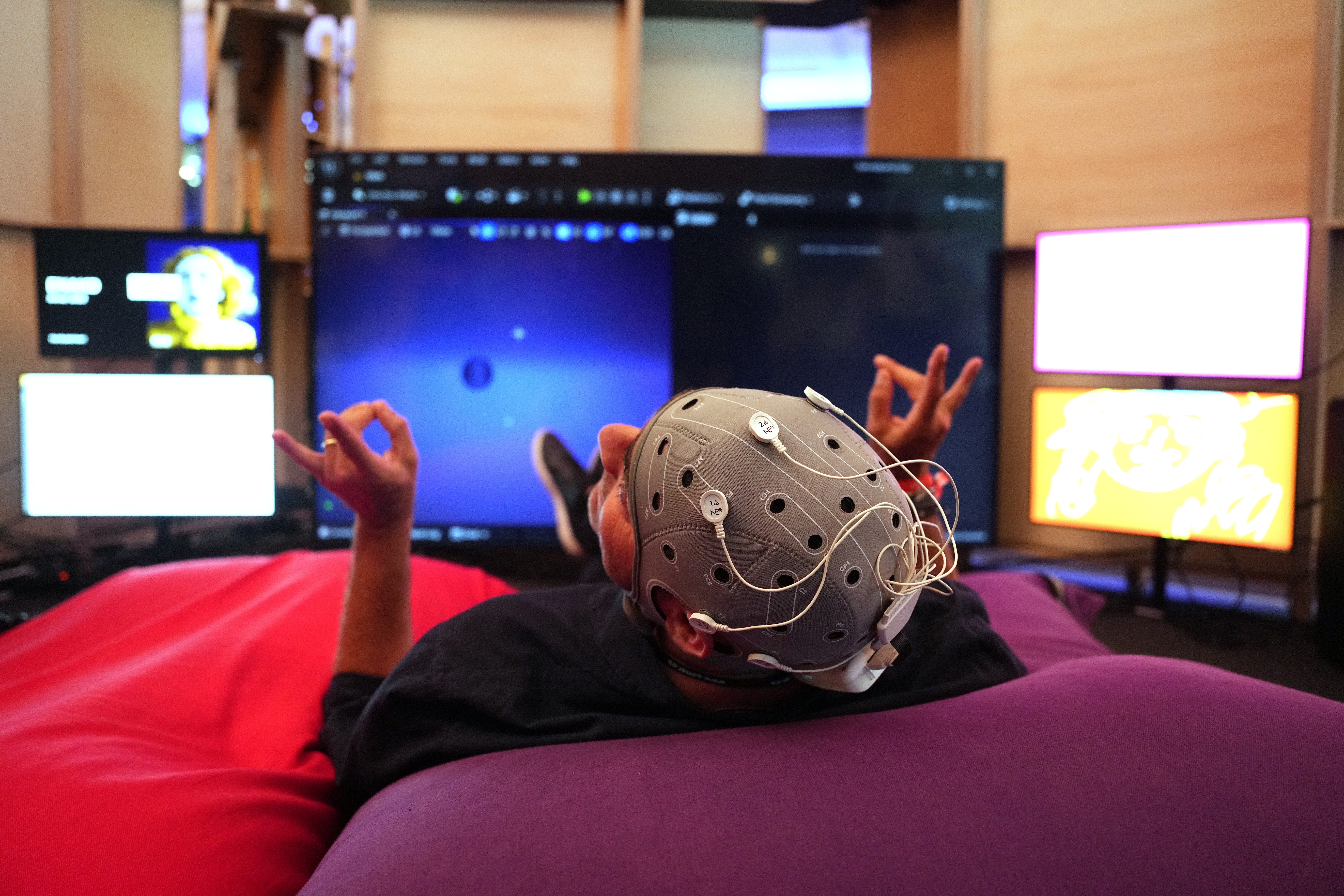 GRAFCAT1625. BARCELONA, 15/06/2023.- Una persona interactúa con la instalación Enakd una interfaz afectiva cerebro-ordenador impulsada por la inteligencia artificial que utiliza las ondas cerebrales para crear imágenes y textos, una de las instalaciones de Sónar+D 2023, dentro del festival Sónar, que este jueves comienza su 30 aniversario con una programación puramente electrónica, en una primera jornada en la que la experimentación estará encabezada por el productor de Weeknd, Oneohtrix Point Never, la música de baile por Black Coffee y las nuevas tecnologías aplicadas a la música por el congreso Sonar+D, centrado en la Inteligencia Artificial. EFE/Alejandro García