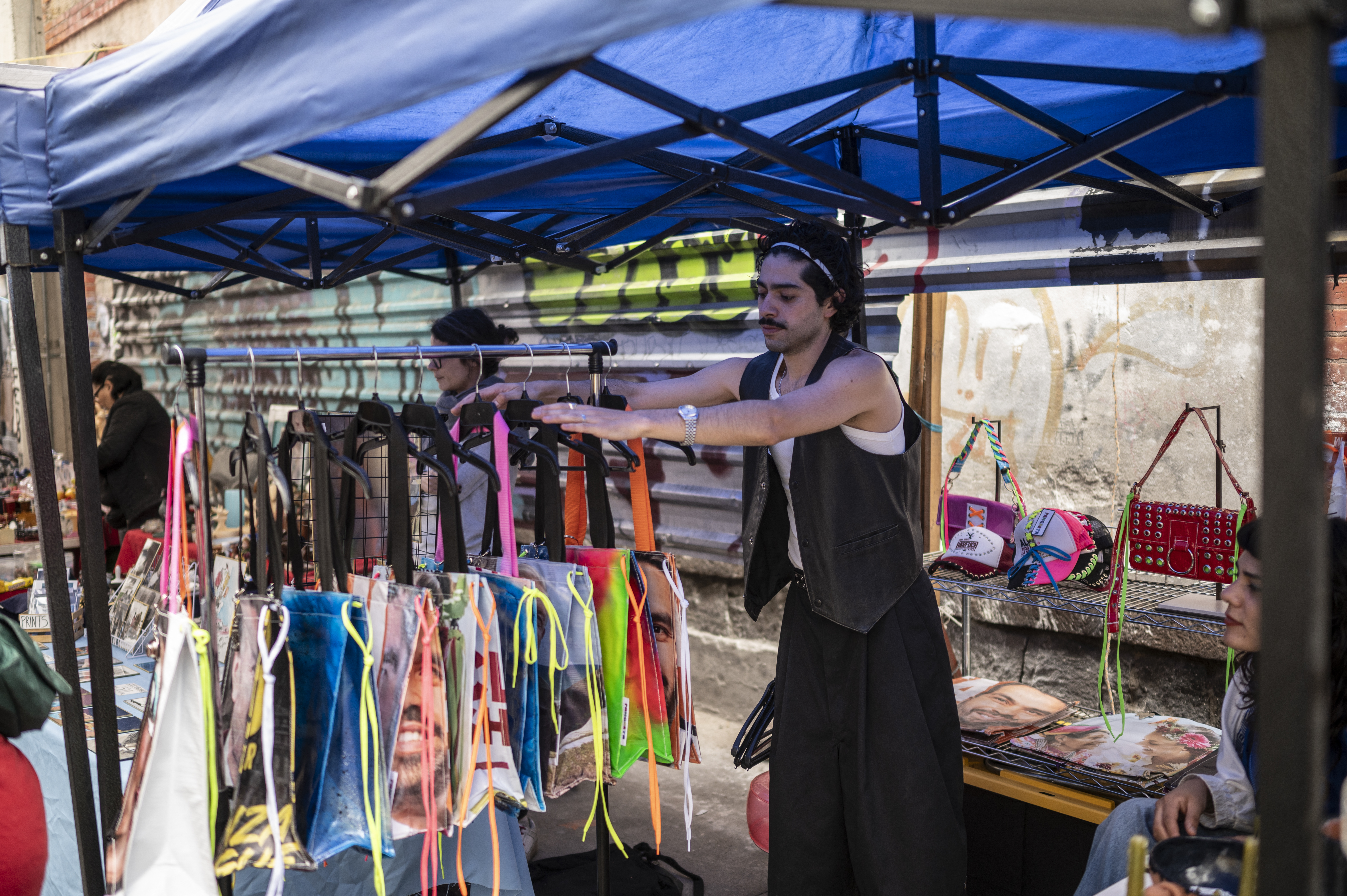 Mexican fashion designer Mizael Perea, 33, places bag designs made from election campaign poster materials at his stall in Lagunilla neighborhood, Mexico City, on June 30, 2024.