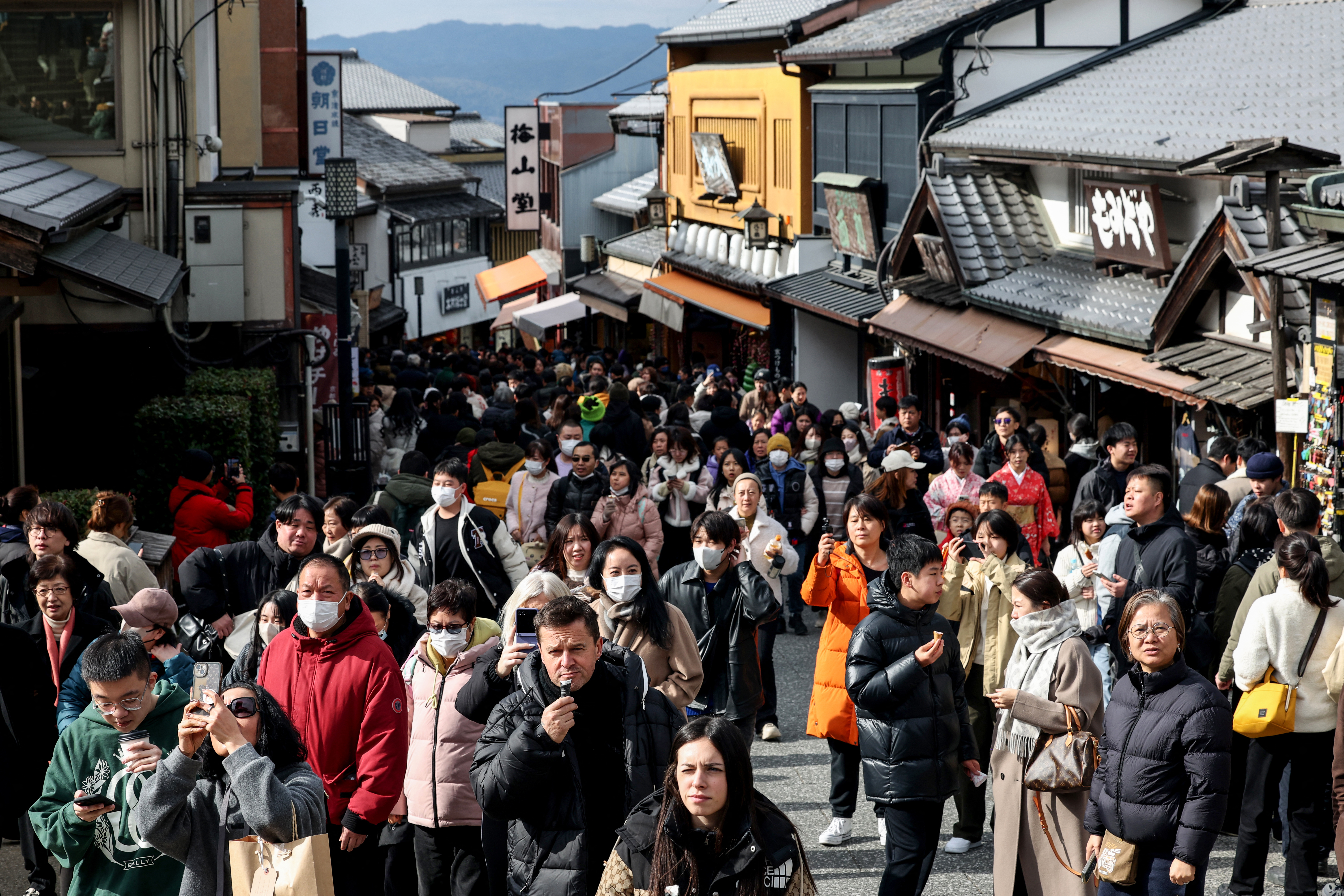 Tourists walk past shops and restaurants up the hill leading to Kiyomizu-dera Temple in the city of Kyoto on January 13, 2025.
