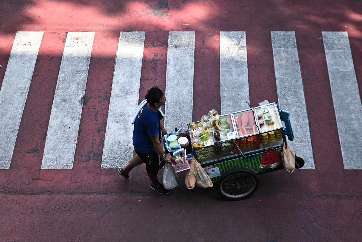 This photo taken on April 30, 2026 shows a street vendor pushing a cart of fresh fruit in Bangkok.
