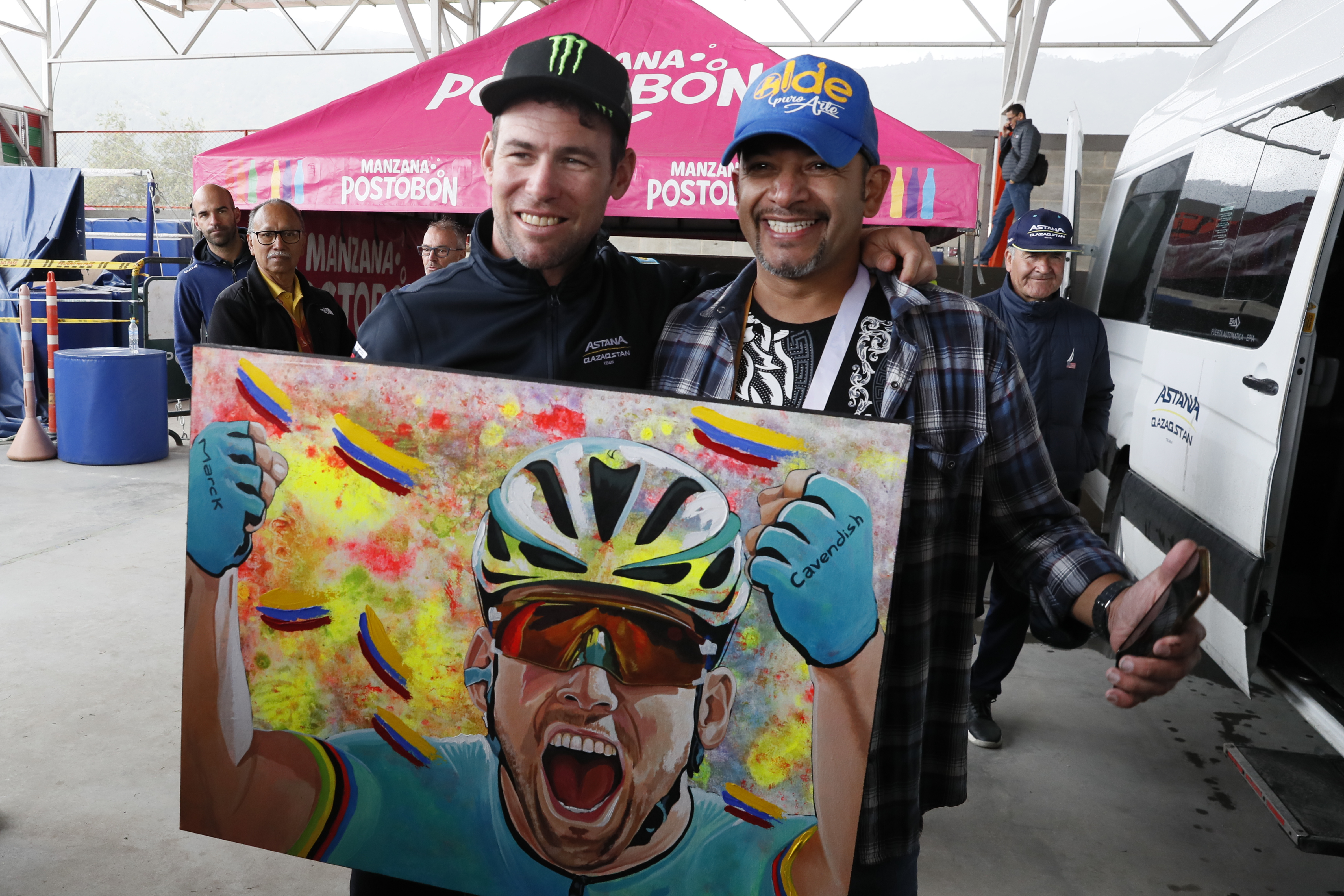 AMDEP6829. COTA (COLOMBIA), 10/02/2024.- El corredor británico Mark Cavendish con un retrato suyo realizado por el pintor colombiano Aldemar Marín (d) hoy, antes de la salida de la quinta etapa de la carrera ciclística Tour Colombia 2024 en Cota (Colombia). EFE Carlos Ortega