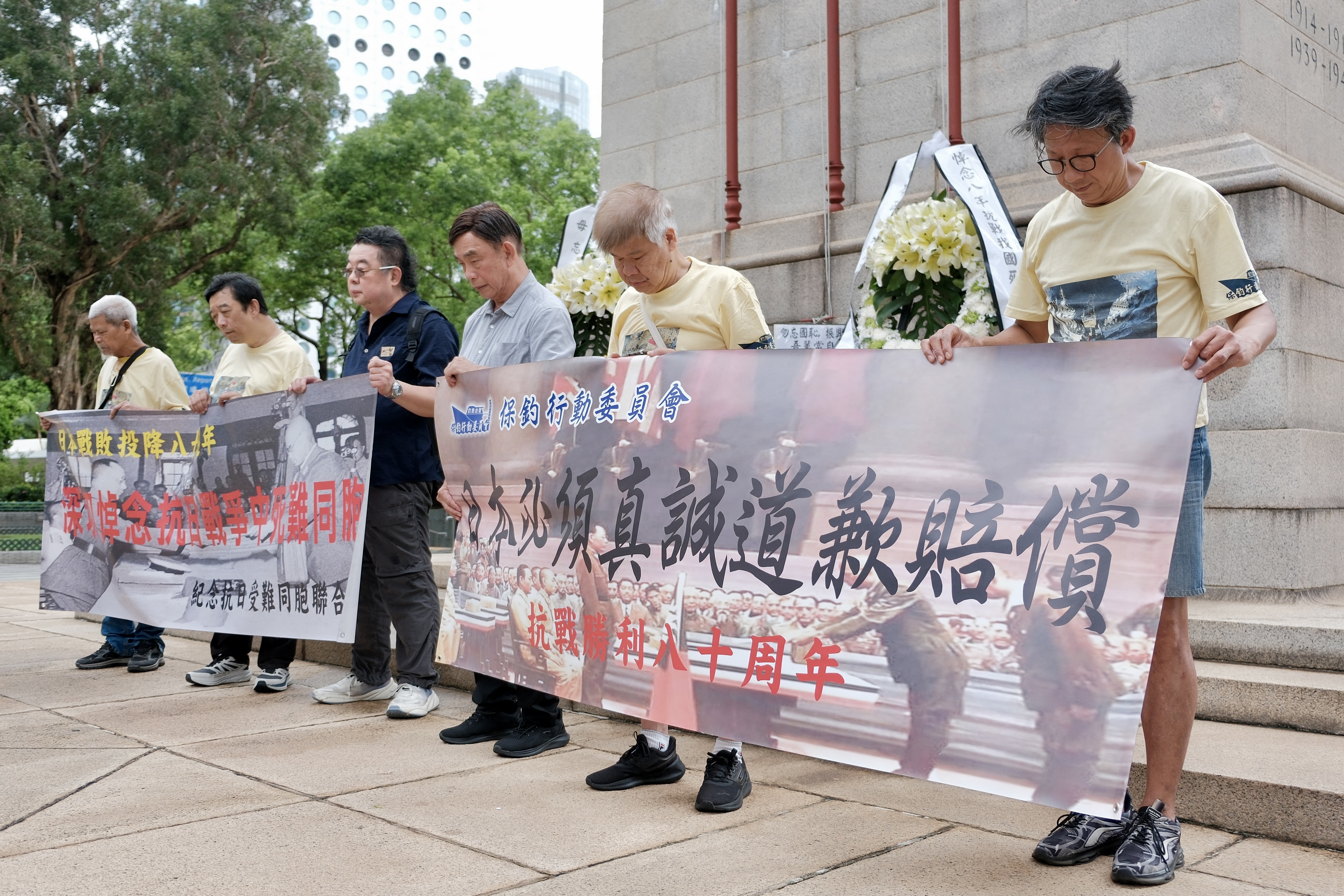Activists pay silent tribute to the victims of war at The Cenotaph war memorial at the Central district in Hong Kong on August 15, 2025, during a small-scale protest march organised to call on Japan to apologise for its invasion of China during World War II, on the 80th anniversary of Japan's announcement of its surrender.