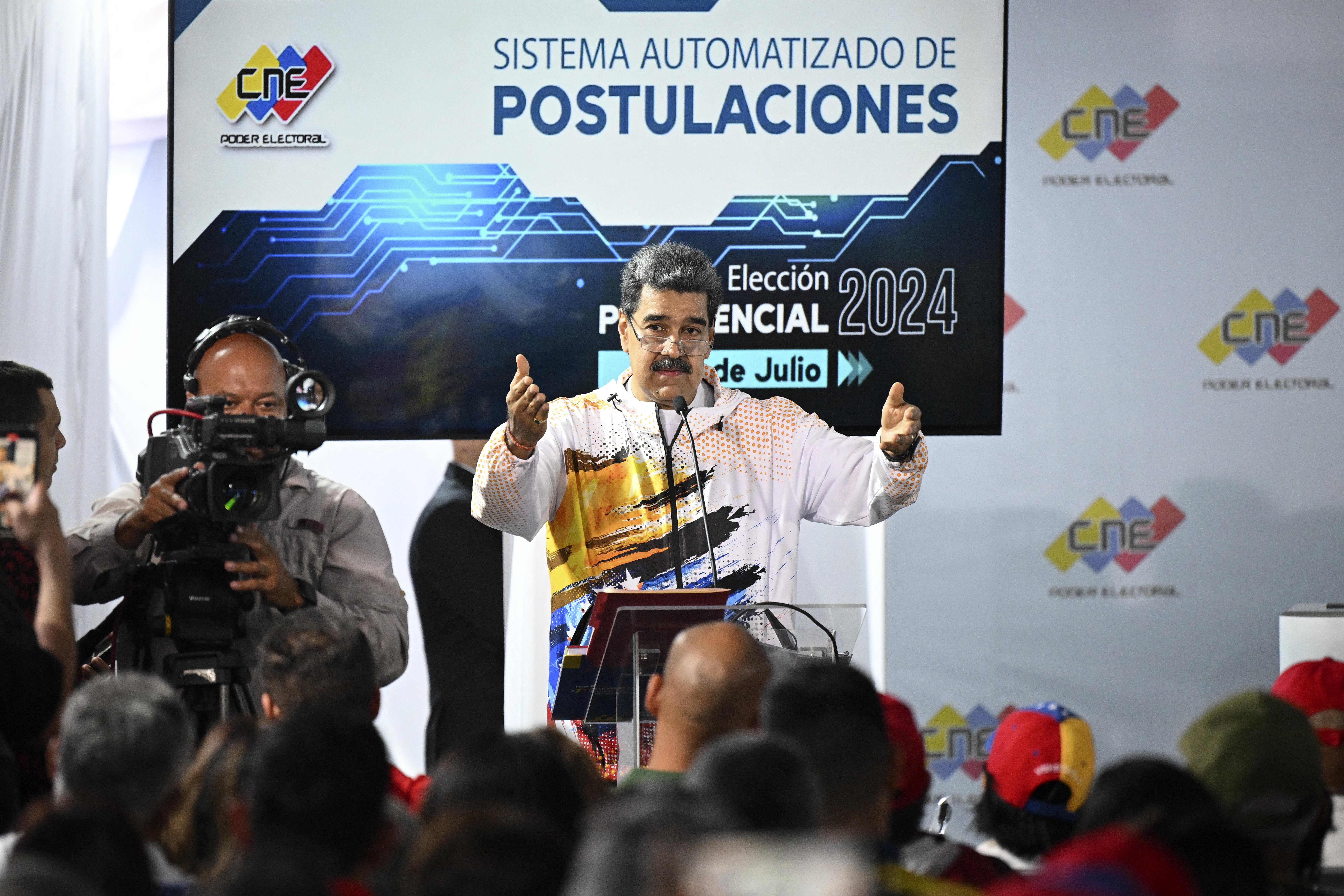 El presidente de Venezuela, Nicolás Maduro, en la sede del Consejo Nacional Electoral (CNE) durante la formalización de su candidatura ante la autoridad electoral venezolana en Caracas el 25 de marzo de 2024. El presidente Nicolás Maduro registró oficialmente el lunes su candidatura en las elecciones de julio, mientras que la oposición quedó bloqueada para inscribir a su aspirante a falta de pocas horas para que se agote el tiempo. Maduro, de 61 años, formalizó su candidatura a la presidencia para un tercer mandato con gran fanfarria, mientras miles de personas acudían a manifestarse detrás de él y del gobernante Partido Socialista Unido de Venezuela.