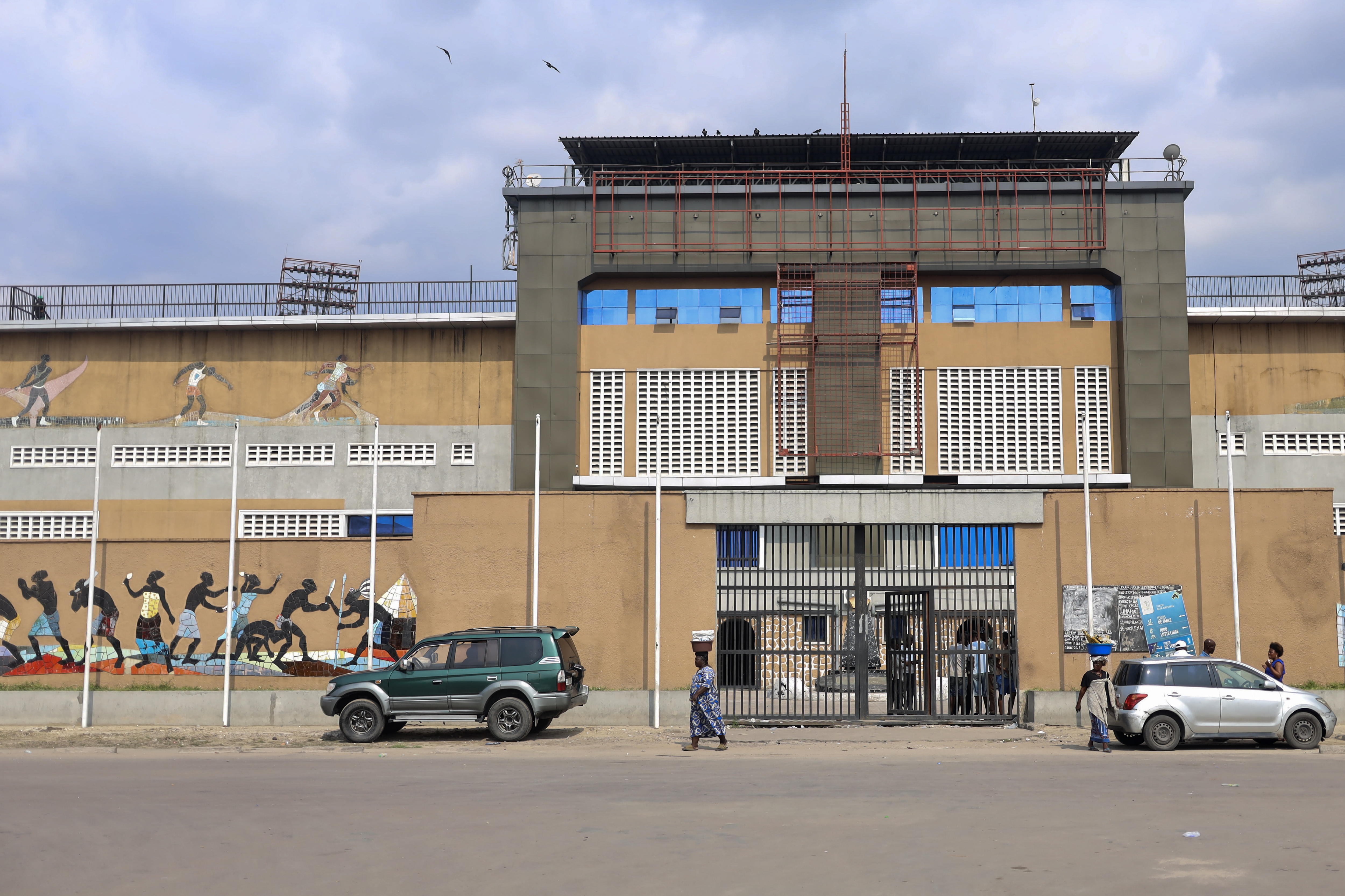 Kinshasa (Congo, The Democratic Republic Of The), 29/10/2024.- People pass by a gate to the Stade Tata Raphael, also known as Father Raphael Stadium, in Kinshasa, Democratic Republic of Congo, 29 October 2024. The stadium was the setting for the 'Rumble in the Jungle', a boxing match between Muhammad Ali and George Foreman for the Undisputed WBC/WBA Heavyweight Championship on 30 October 1974. The match was attended by about 60,000 people. EFE/EPA/STR