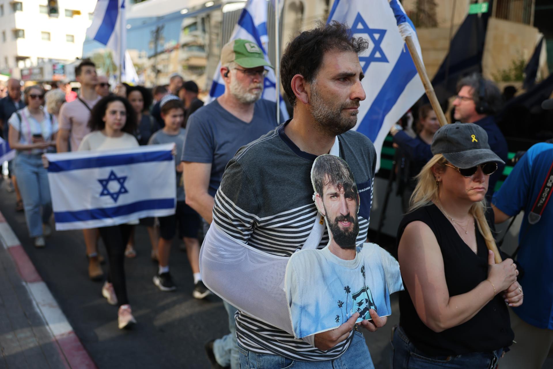 Rishon LeZion (Israel), 15/10/2025.- A man carries a picture of late Israeli hostage Guy Illouz as mourners escort his coffin during his funeral procession in Rishon LeZion, Israel, 15 October 2025. Guy Illouz was kidnapped by Hamas on October 7th from the Nova music festival and killed in captivity. His body was returned during ceasefire deal on October 13. Twenty-one bodies of Israeli hostages still remain in Hamas captivity. EFE/EPA/ABIR SULTAN