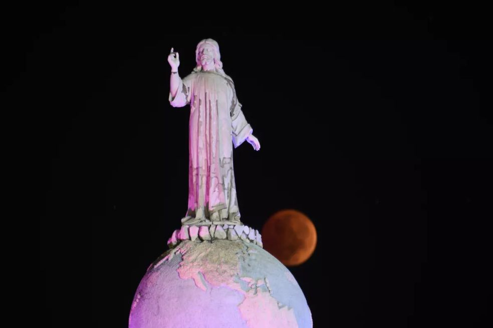La luna del Castor completamente eclipsada pasa detrás del Monumento al Divino Salvador del Mundo en San Salvador, El Salvador.