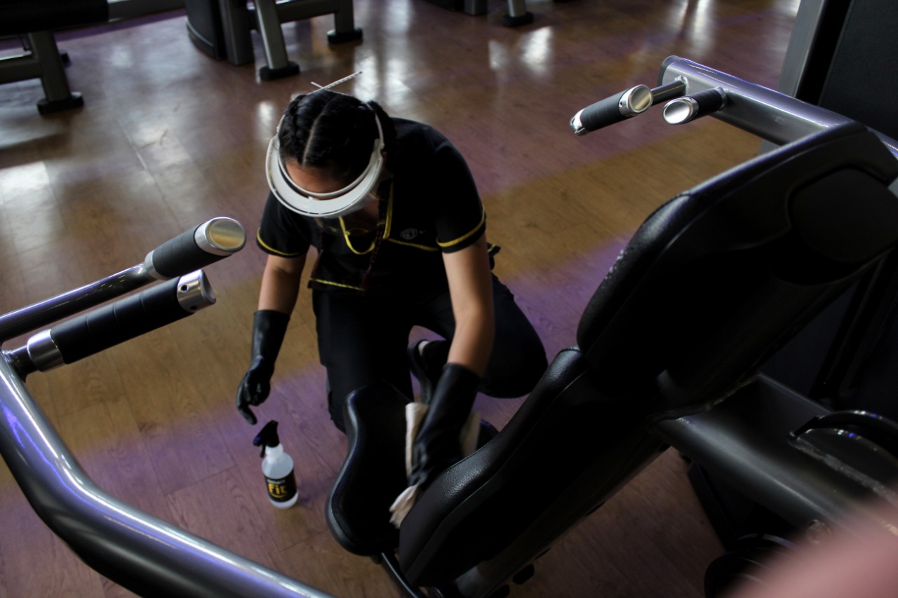 Una mujer limpia una máquina de gimnasio
