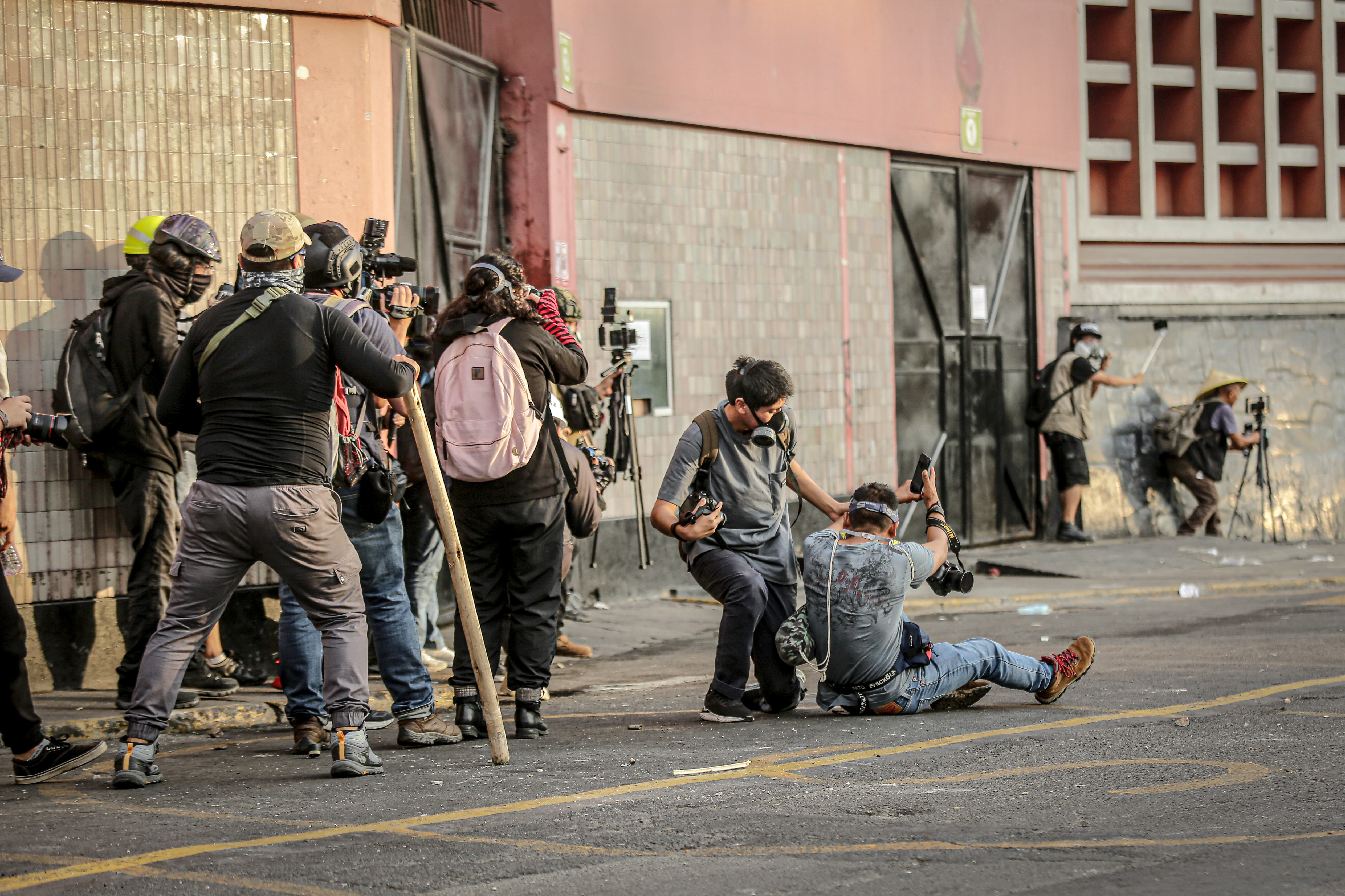AME7303. LIMA (PERÚ), 19/01/2023.- Fotógrafos y miembros de la prensa se protegen mientras cubren las confrontaciones entre Policía y manifestantes en el Parque Universitario, durante la llamada "toma de Lima" hoy, en Lima (Perú). Miles de peruanos venidos de diversos puntos del país se congregaron este jueves en la capital en la denominada "toma de Lima", para exigir la renuncia de la presidenta Dina Boluarte, el cierre del Congreso y expresar su hartazgo por el olvido del Estado que consideran que padecen. EFE/ Str