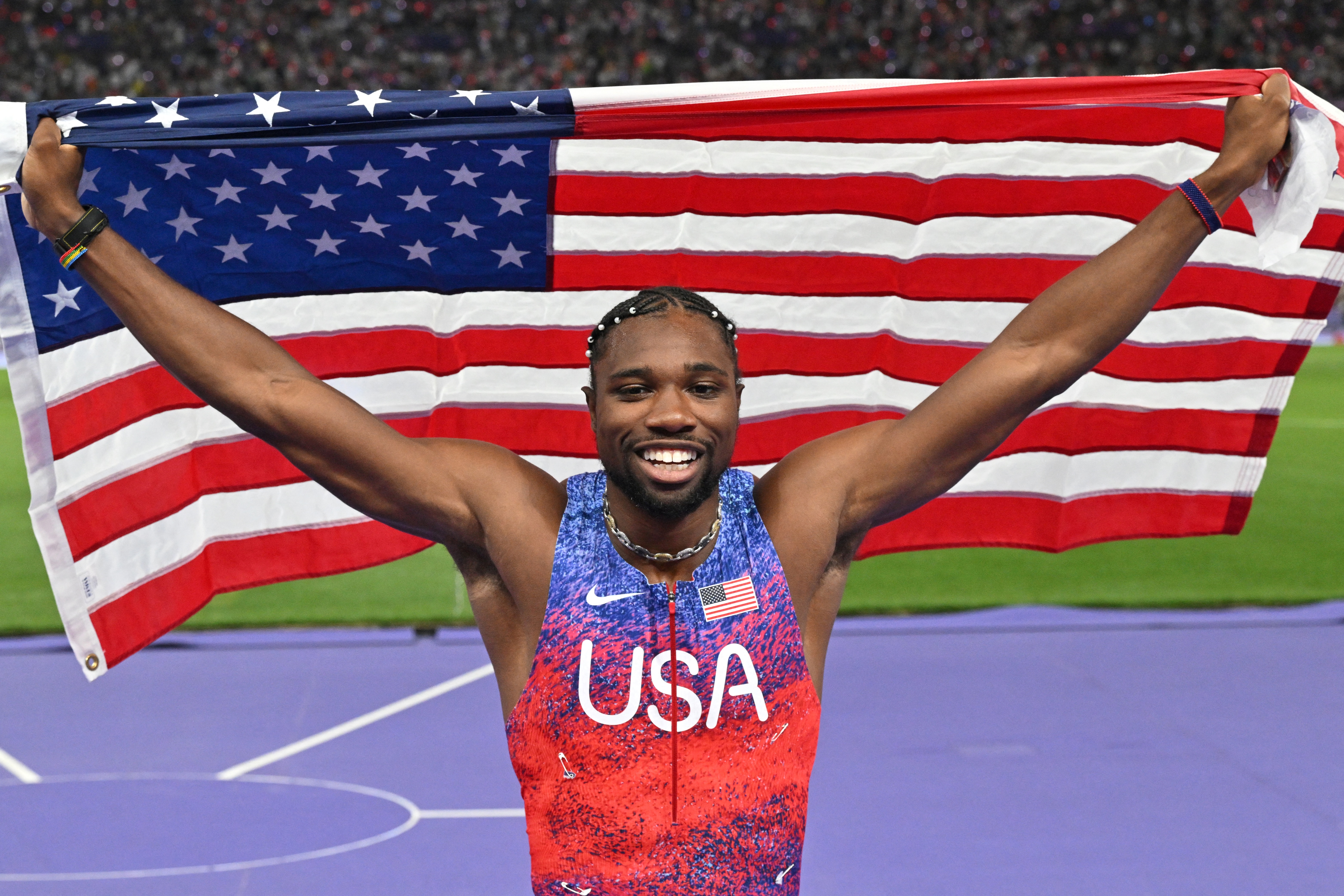 TOPSHOT - US' Noah Lyles (C) celebrates after winning the men's 100m final of the athletics event at the Paris 2024 Olympic Games at Stade de France in Saint-Denis, north of Paris, on August 4, 2024. (Photo by Andrej ISAKOVIC / AFP)