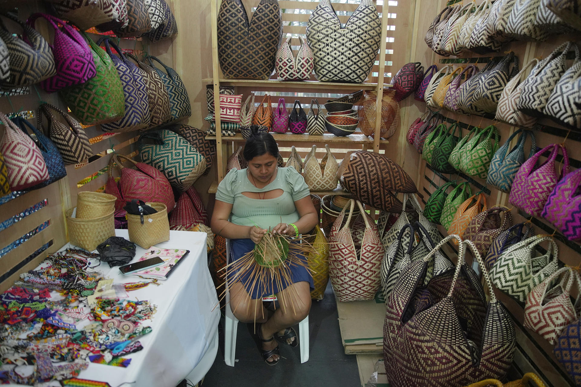 AME9939. CALI (COLOMBIA), 13/08/2025.- Una mujer teje un bolso artesanal en el Festival de Música del Pacífico Petronio Álvarez este miércoles, en Cali (Colombia). El Petronio Álvarez en su XXIX versión, que se celebra del 13 al 17 de agosto, es el evento de cultura afro más grande de Latinoamérica. EFE/ Ernesto Guzmán
