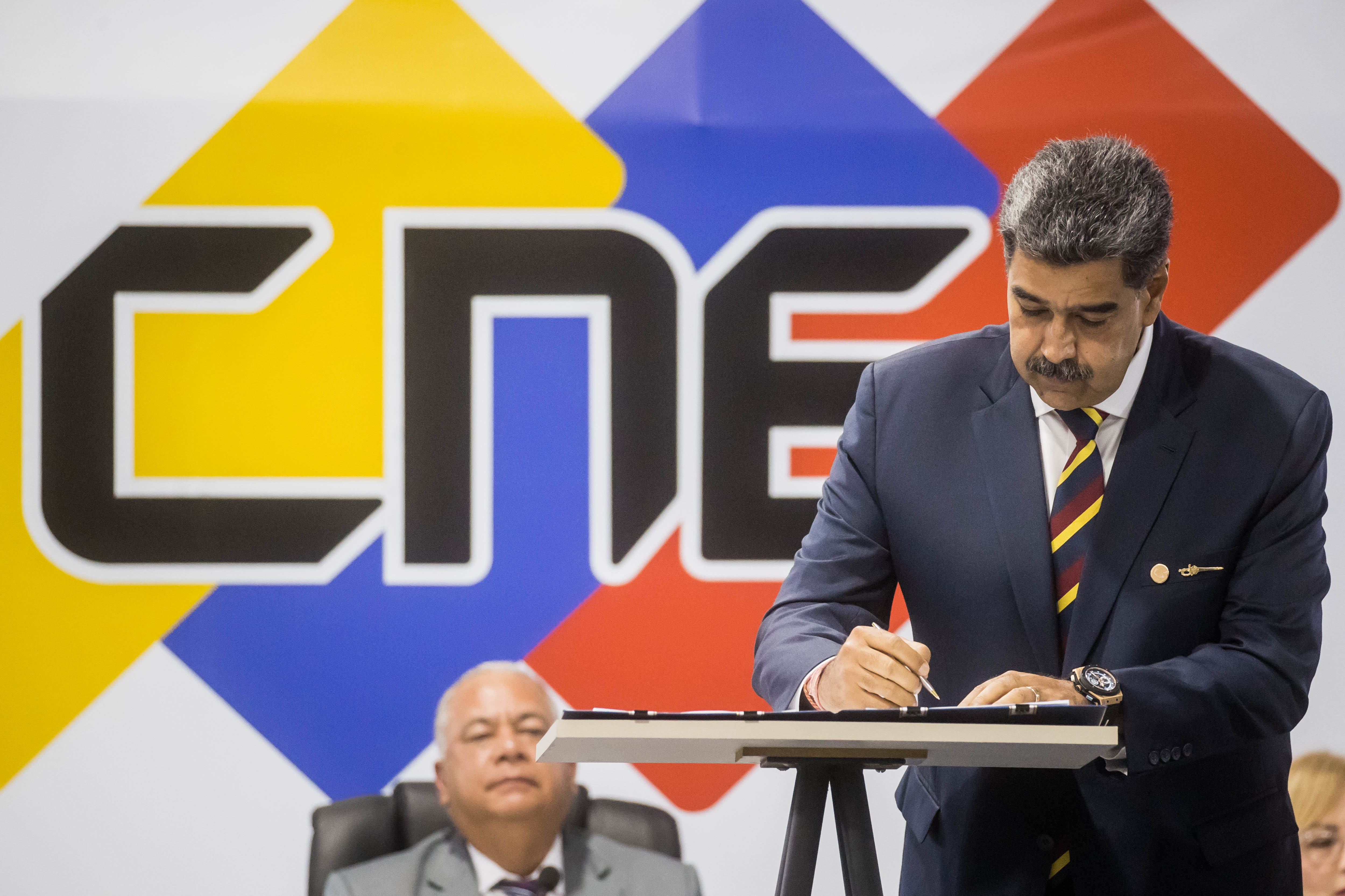 AME5459. CARACAS (VENEZUELA), 20/06/2024.- El presidente de Venezuela y candidato a la reelección, Nicolás Maduro, firma un documento en la sede principal del Consejo Nacional Electoral (CNE) este jueves, en Caracas (Venezuela). Nueve de los diez candidatos a las elecciones presidenciales del 28 de julio en Venezuela, incluyendo al presidente Nicolás Maduro y exceptuando al opositor Edmundo González Urrutia, suscribieron este jueves, ante el Consejo Nacional Electoral (CNE), un acuerdo que los obliga a reconocer el resultado que el ente rector de los comicios anuncie tras el recuento de las votaciones, sin dejar margen para posibles reclamaciones. EFE/ Miguel Gutiérrez