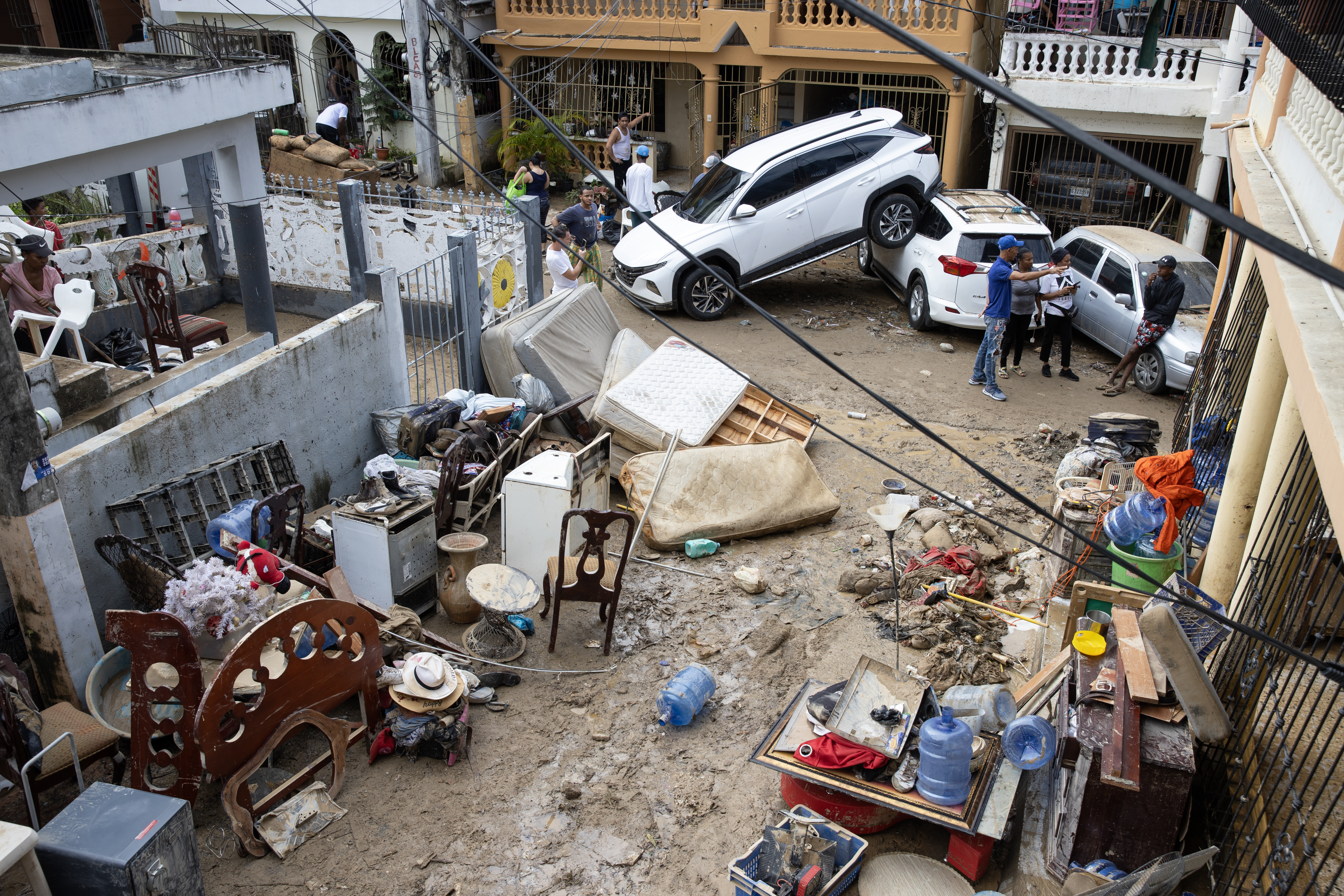 ACTUALIZA INFORMACIÓN SANTO DOMINGO (REPÚBLICA DOMINICANA), 19/11/2023.- Personas quitan el lodo de sus muebles, junto a varios vehículos que fueron arrastrados por la corriente, hoy en Santo Domingo (República Dominicana). Las autoridades dominicanas confirmaron este domingo la muerte de al menos 14 personas como consecuencia de las lluvias que afectan al país desde el pasado viernes y que ha descargado el mayor volumen de agua registrado jamás en el país caribeño. EFE/Orlando Barría