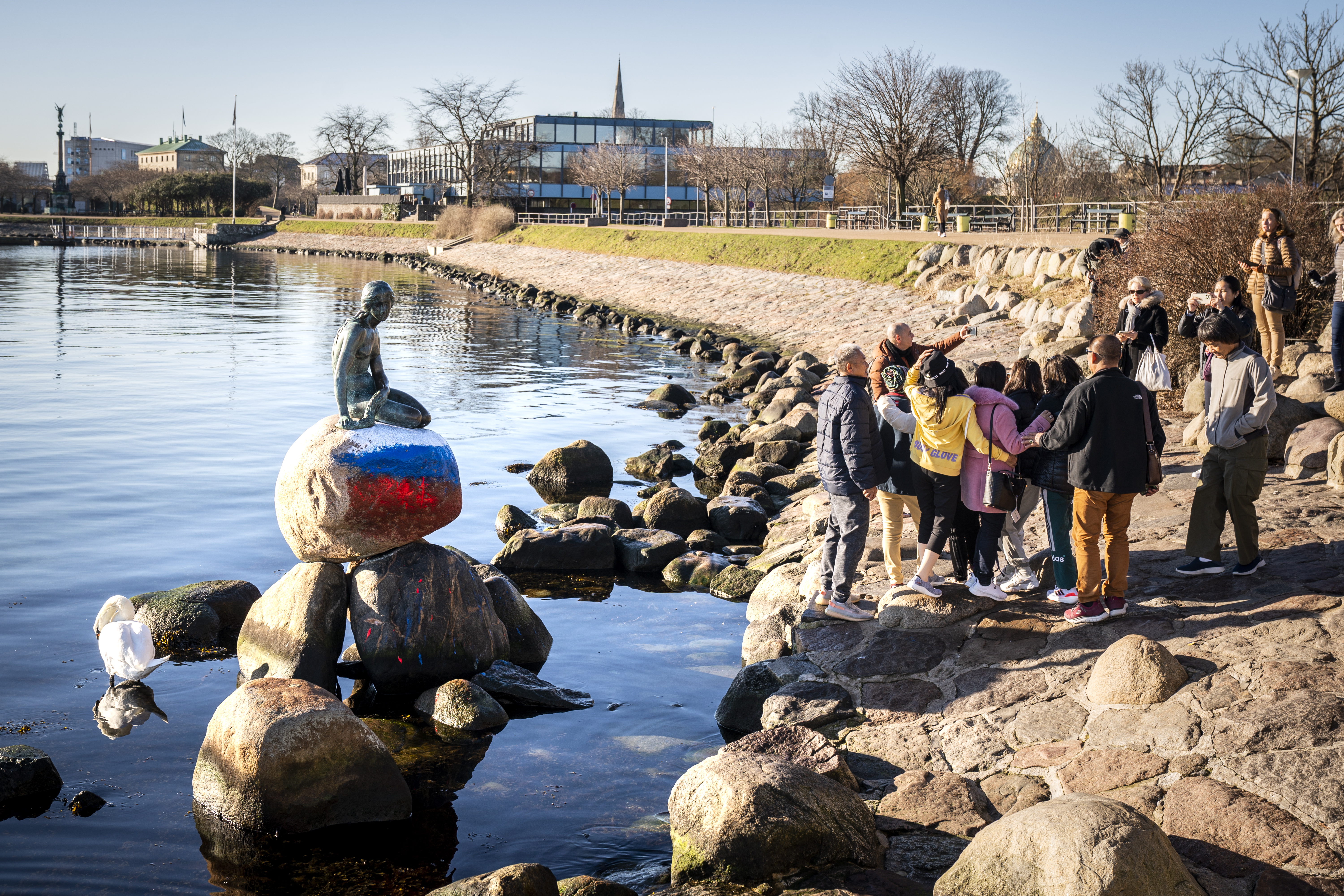 Copenhagen (Denmark), 02/03/2023.- People pose for a picture with the vandalized Little Mermaid statue, with the Russian flag painted on the stone where it sits on, in Copenhagen, Denmark, 02 March 2023. The Little Mermaid was created by the sculptor Edvard Eriksen and modeled after his wife, Eline. The figure is the sculptor's embodiment of the mermaid in Hans Christian Andersen's famous fairy tale 'The Little Mermaid'. (Abierto, Dinamarca, Rusia, Copenhague) EFE/EPA/IDA MARIE ODGAARD DENMARK OUT