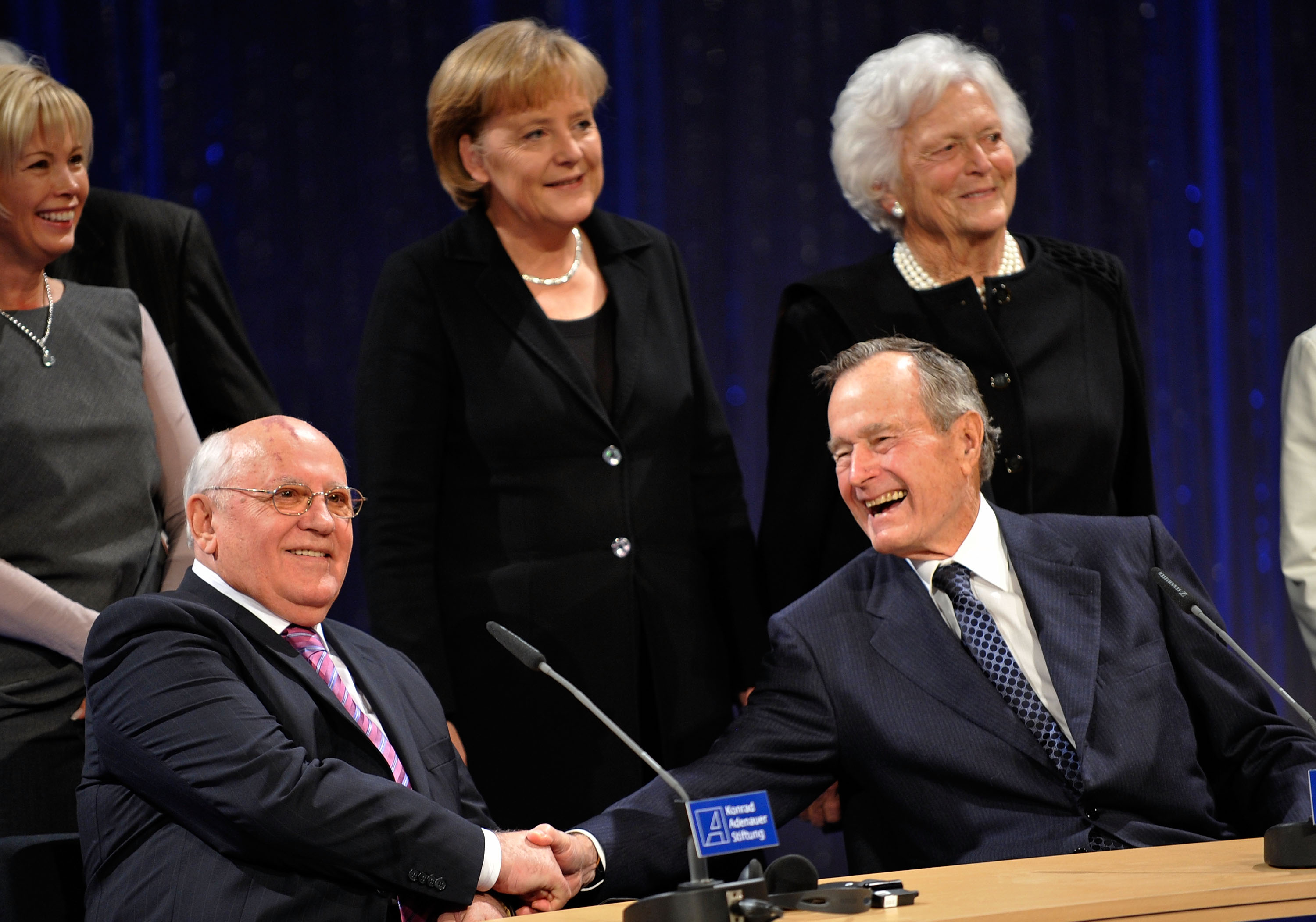 El expresidente estadounidense George H. W. Bush le da la mano al expresidente soviético, mientras la canciller alemana Angela Merkel y la esposa de Bush, Barbara Bush (der.), observan un evento en el Friedrichstadtpalast el 31 de octubre de 2009 en Berlín.