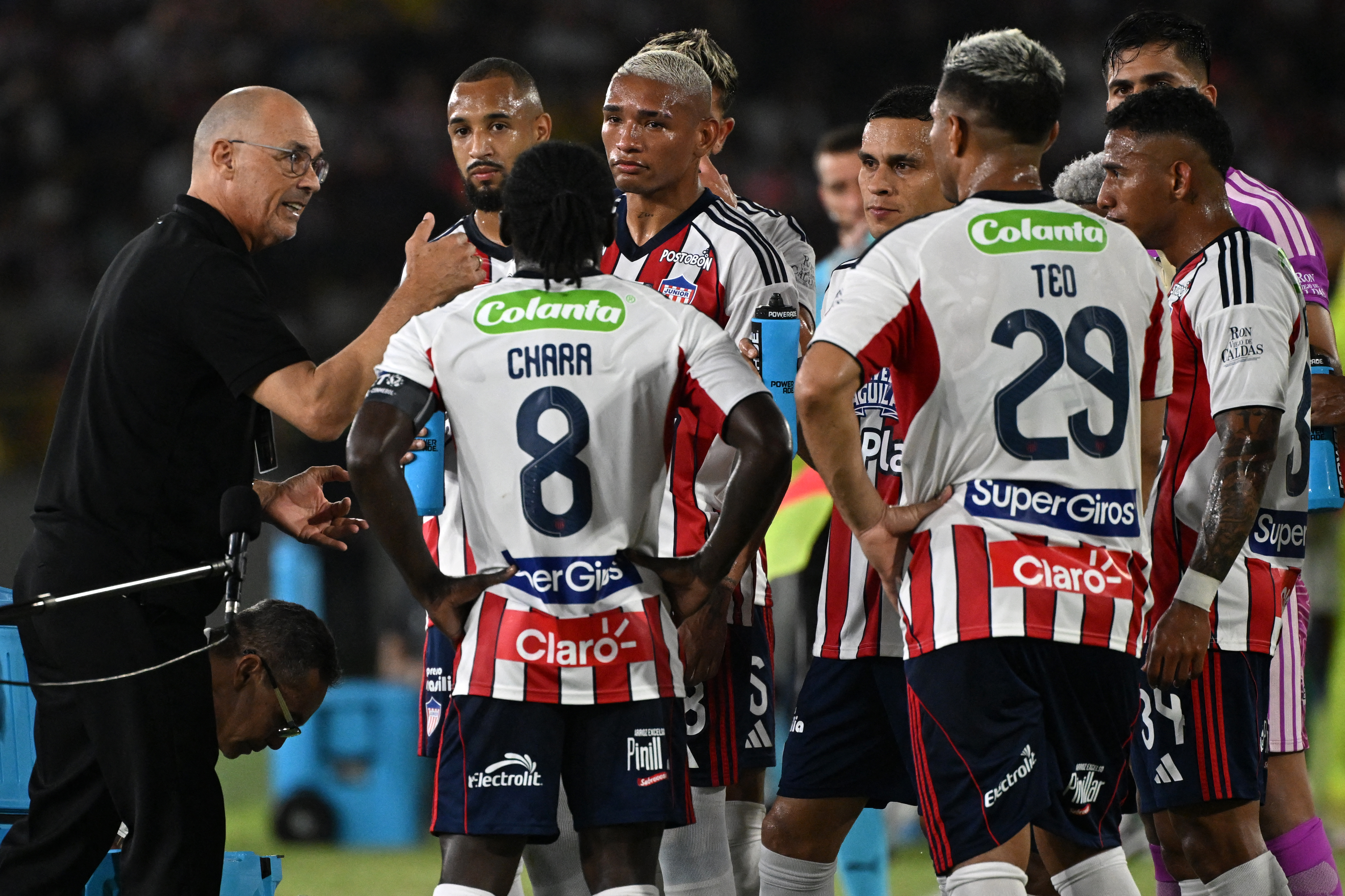 Junior's Uruguayan head coach Alfredo Arias speaks with his players during the Copa Libertadores group stage football match between Colombia's Junior and Brazil's Palmeiras at the Olimpico Jaime Moron Leon stadium in Cartagena, Bolivar department, Colombia, on April 8, 2026. (Photo by Luis ACOSTA / AFP)