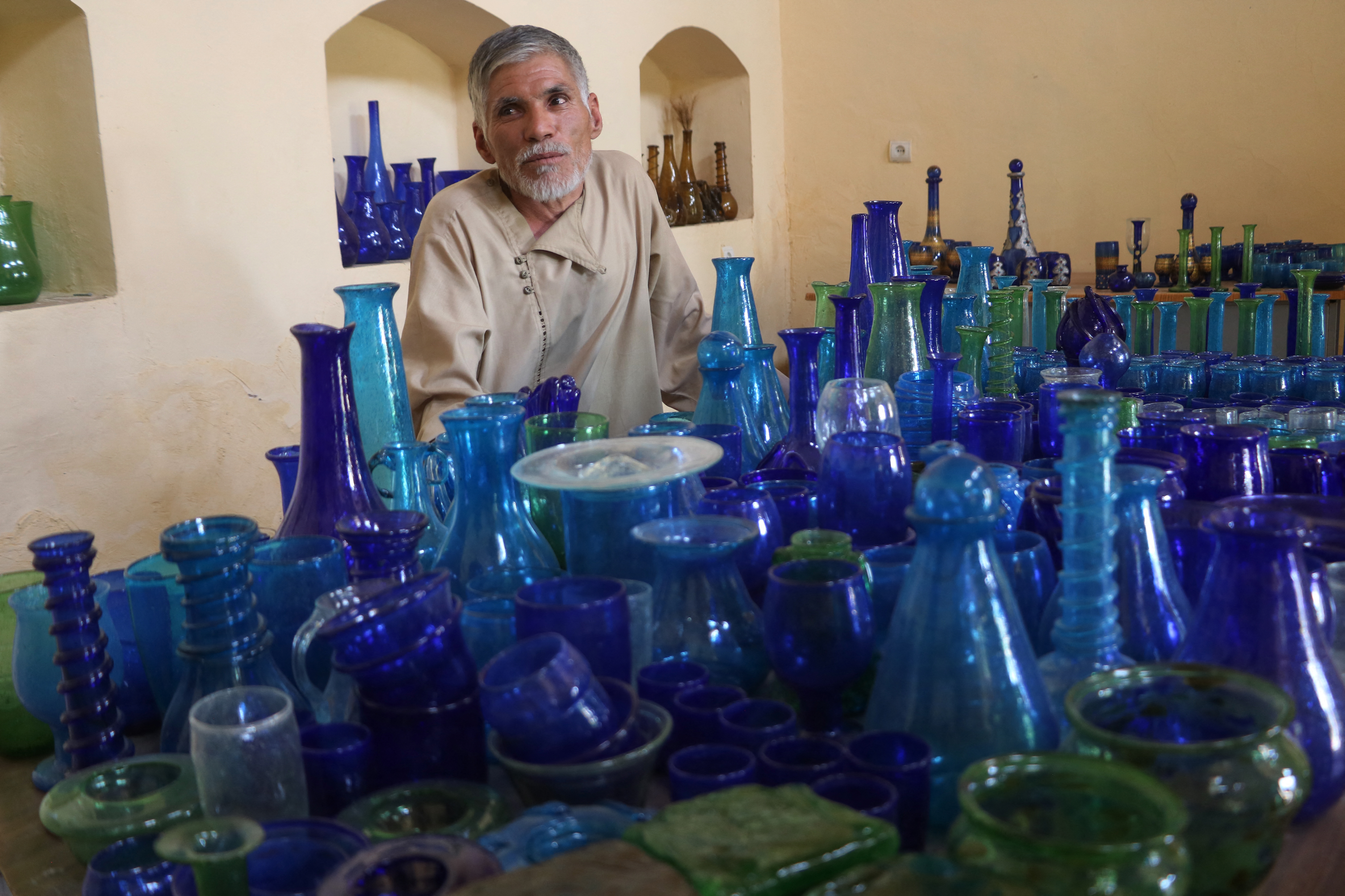 In this photograph taken on August 12, 2024, Ghulam Sakhi Saifi, an Afghan glassblower, looks on while arranging glassware at his shop in Afghanistan's western city of Herat.