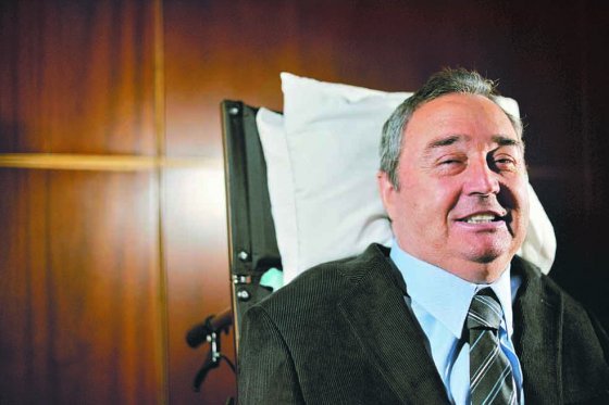 El profe Montoya se pone de pie pero con ayuda de soportes