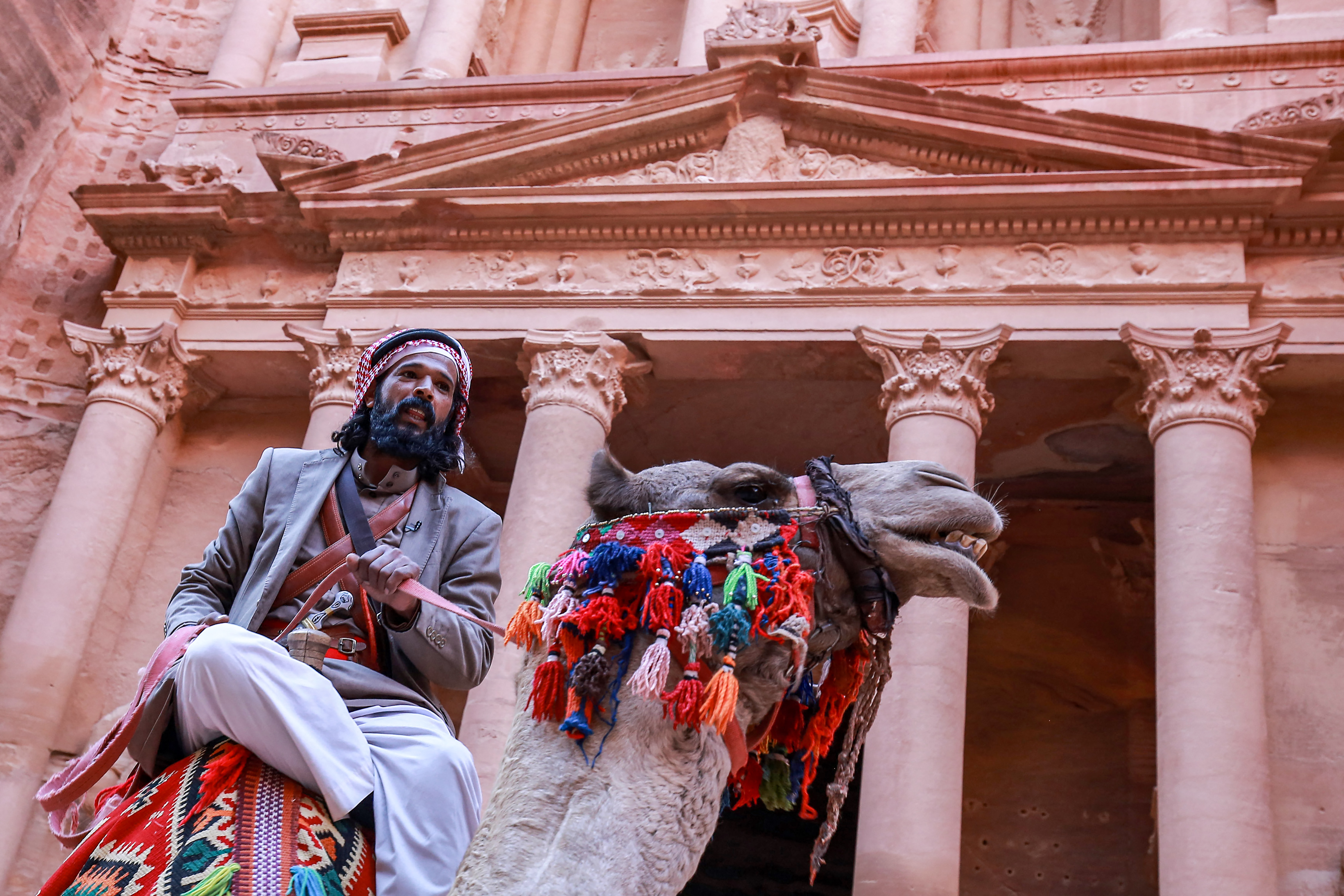 Hussien Bdoul, un guía de camellos de 35 años, monta su camello fuera del Tesoro en las ruinas de la antigua ciudad nabatea de Petra en el sur de Jordania el 12 de diciembre de 2022.