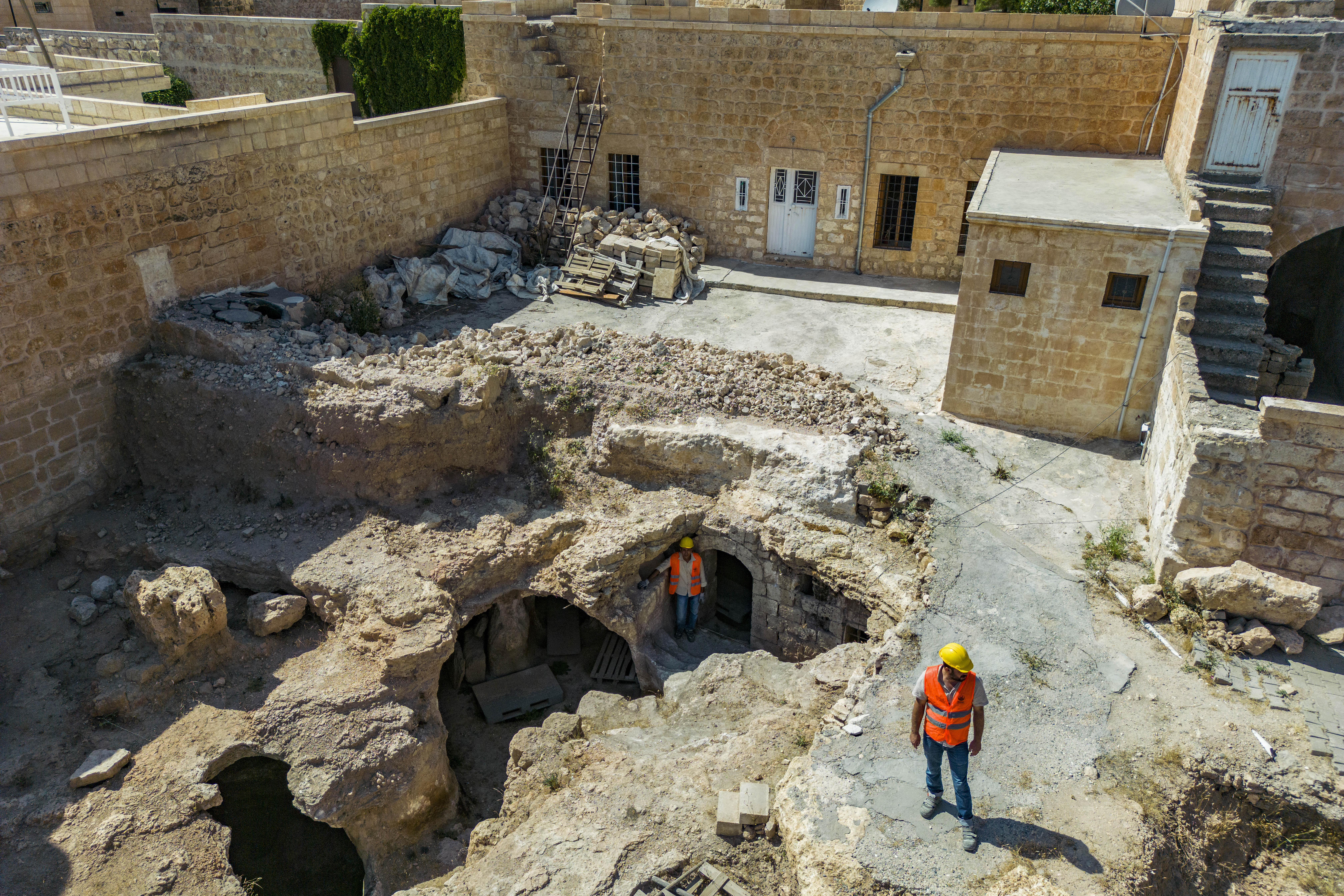 This aerial view shows municipal employees working outside the Matiate archaeological site underneath the town in Midyat in Mardin province, southeastern Turkey, on July 1, 2024.