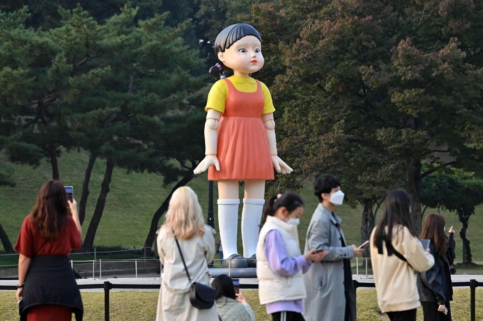 Un grupo de personas se reúne frente a un modelo de la muñeca llamada 'Younghee', que aparece en la serie de Netflix "El juego del calamar".