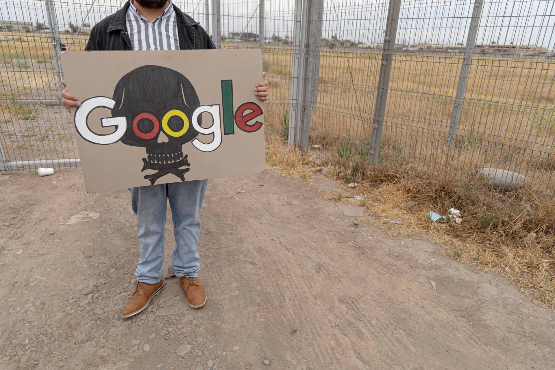 ACOMPAÑA CRÓNICA: CHILE CENTROS DATOS AME5816. SANTIAGO (CHILE), 06/11/2025.- Fotografía del 21 de octubre de 2025 que muestra una persona sosteniendo un cartel afuera de un recinto privado perteneciente a Google en Cerrillos, Santiago (Chile). Chile se ha posicionado entre los países más atractivos de Latinoamérica para albergar centros de datos para la inteligencia artificial (IA) por su abundante energía renovable, buena conectividad y políticas públicas favorables, en medio de un pulso con las comunidades afectadas que alzan la voz contra los impactos ambientales de estas infraestructuras. EFE/ Ailen Díaz
