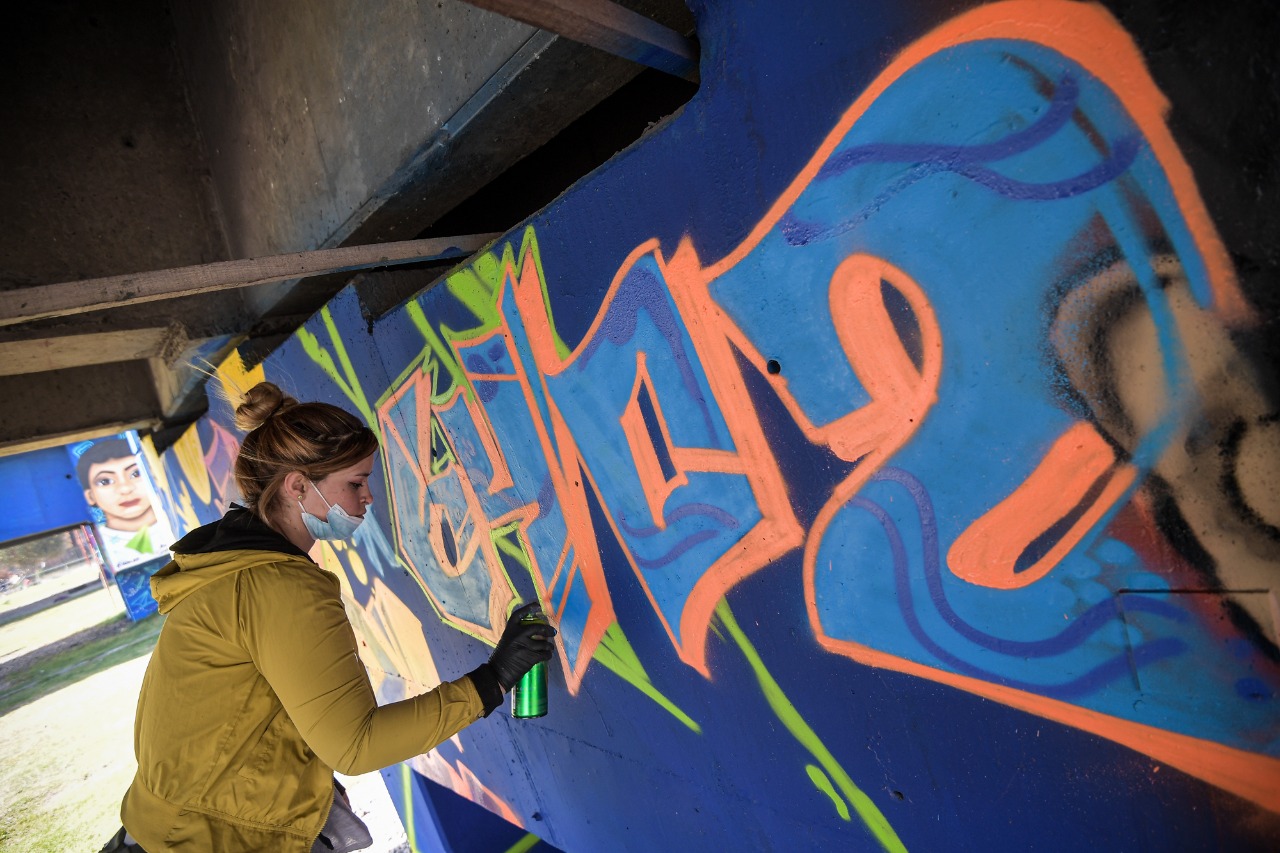 Una mujer hace un grafiti en una pared