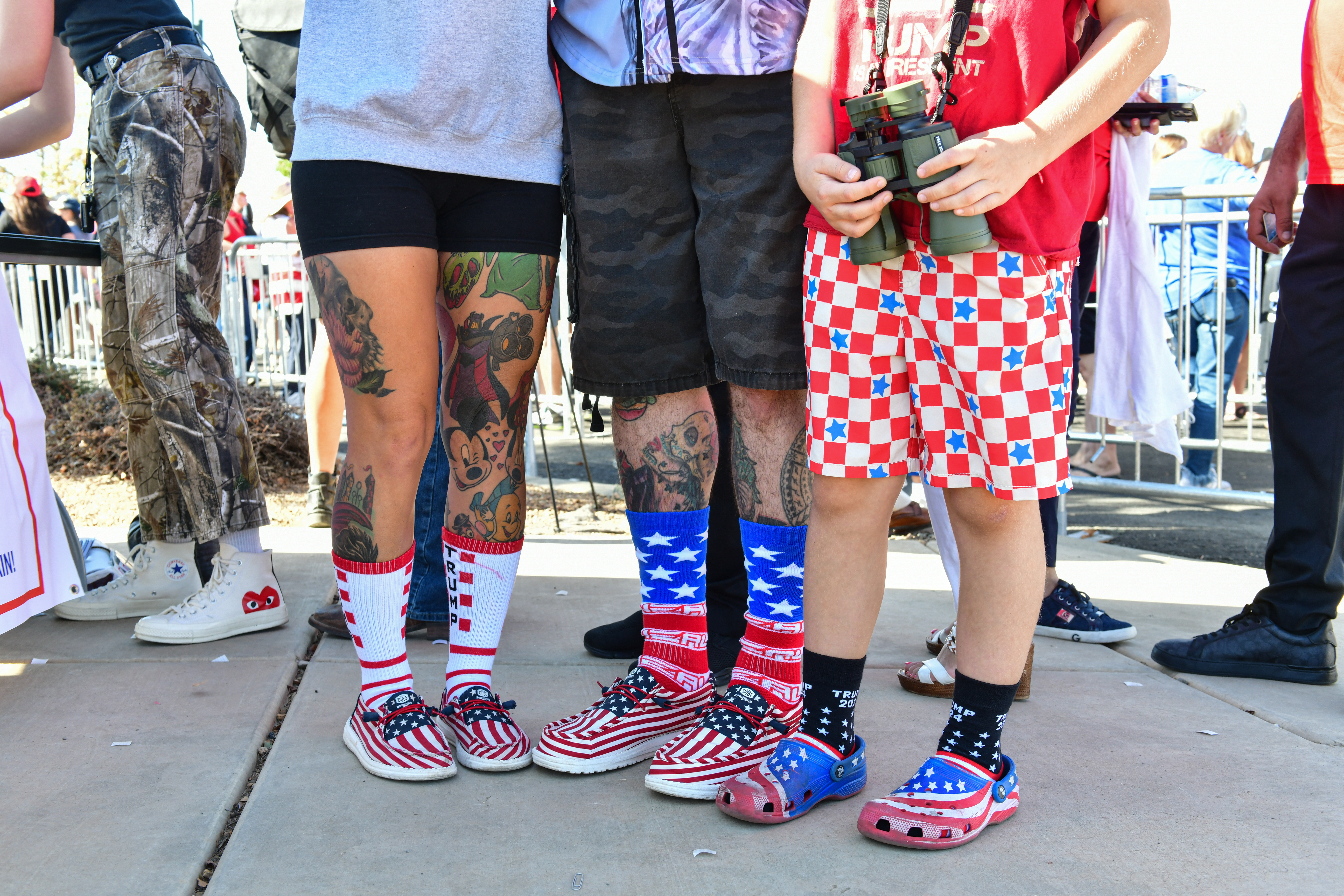 Karina and Rickey Sanderson with their son, Kayden, 10, wear red white and blue socks and shoes as they wait to enter a campaign rally for former US President and Republican presidential candidate Donald Trump at Findlay Toyota Arena in Prescott Valley, Arizona, on October 13, 2024. (Photo by Caitlin O'Hara / AFP)
