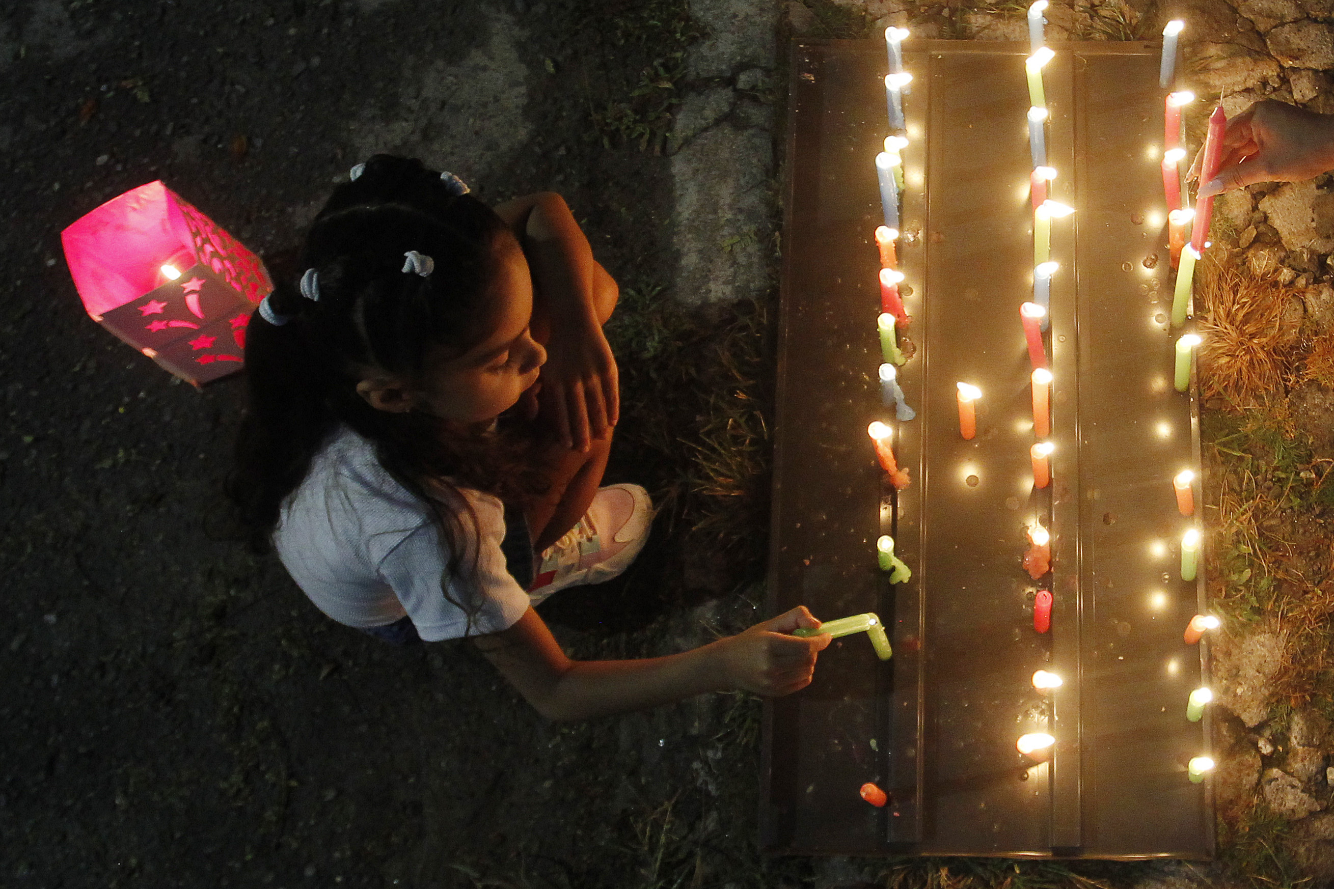 MED108 -MEDELLÍN(COLOMBIA), 07/12/2023. Una niña enciende una vela durante la tradicional noche de las velitas hoy, en Medellín (Colombia). Esta costumbre colombiana celebra el día de la Inmaculada Concepción y marca el inicio de las conmemoraciones navideñas. EFE/Luis Eduardo Noriega Arboleda